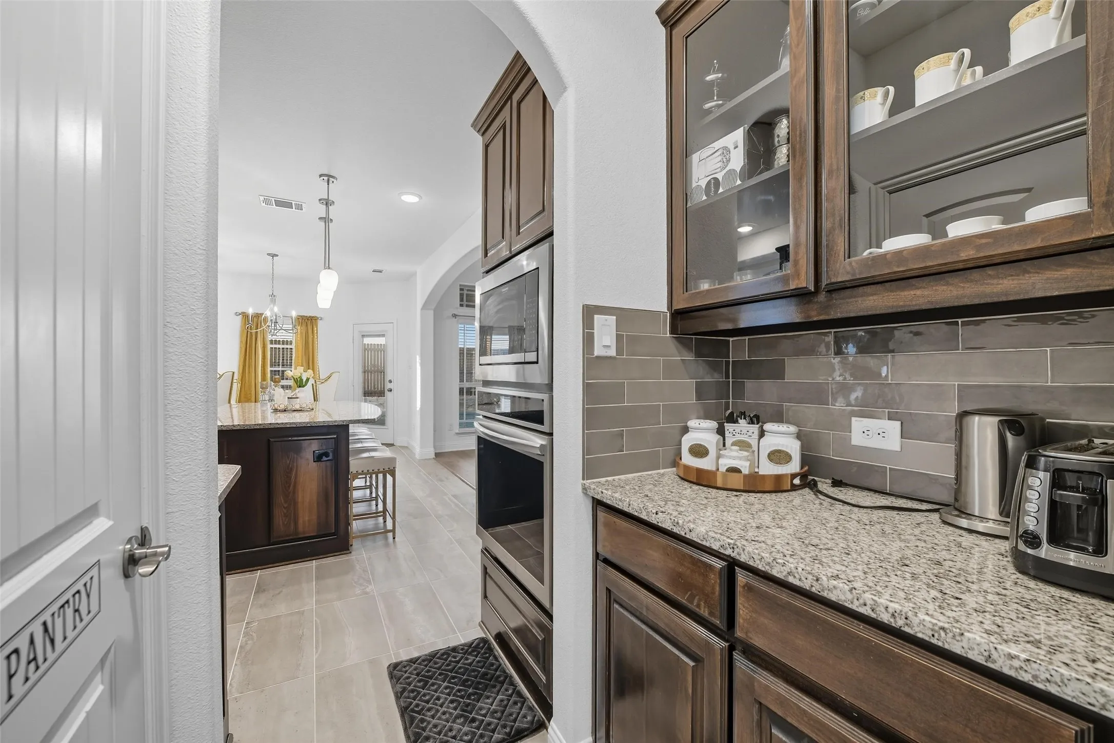 Kitchen featuring built-in stainless steel appliances, granite countertops, and dark wood-finish cabinetry
