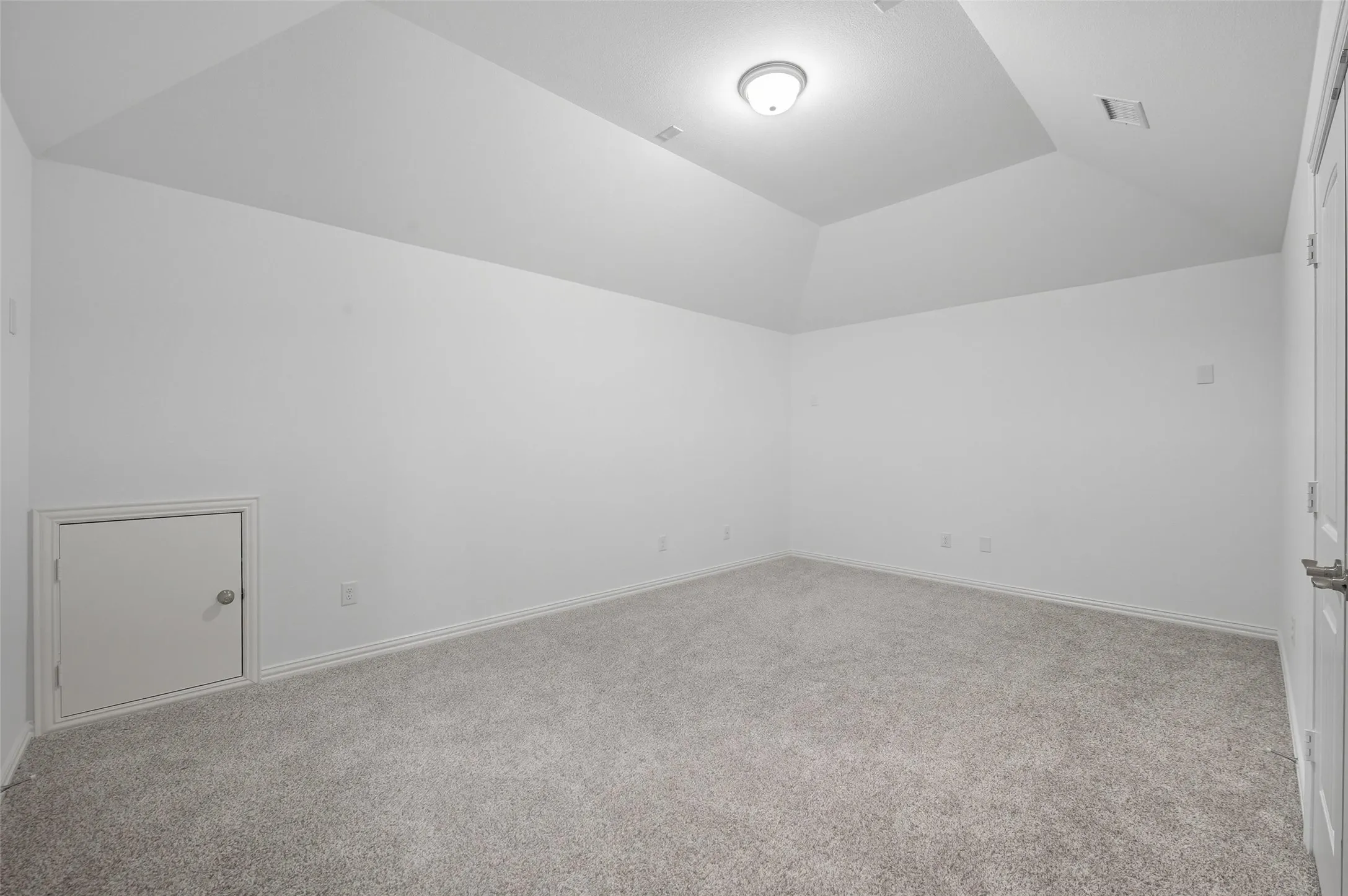 Carpeted interior room with white walls and a vaulted ceiling