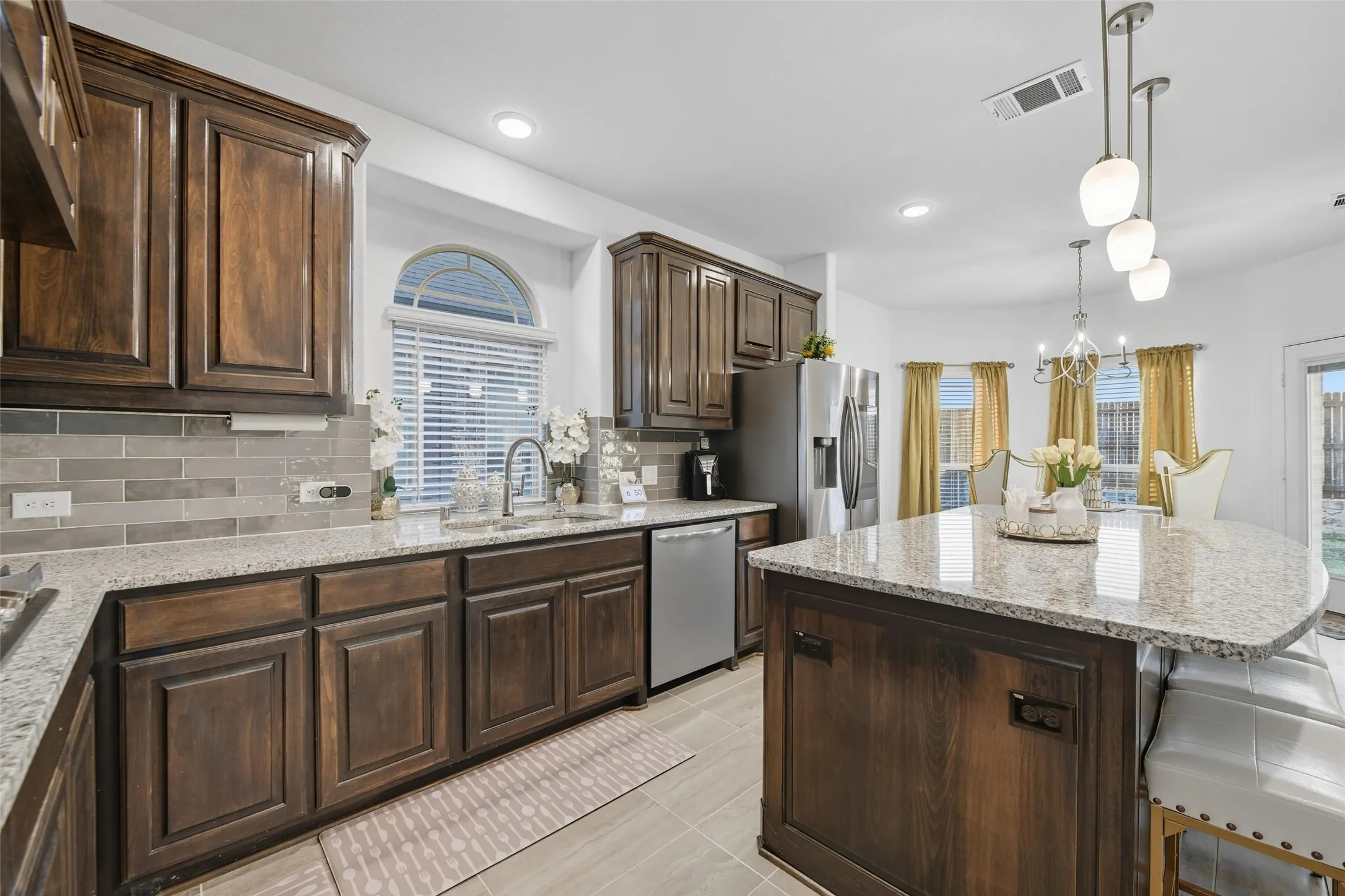 Kitchen featuring wood-finish cabinetry, light-toned granite countertops, and a subway tile backsplash