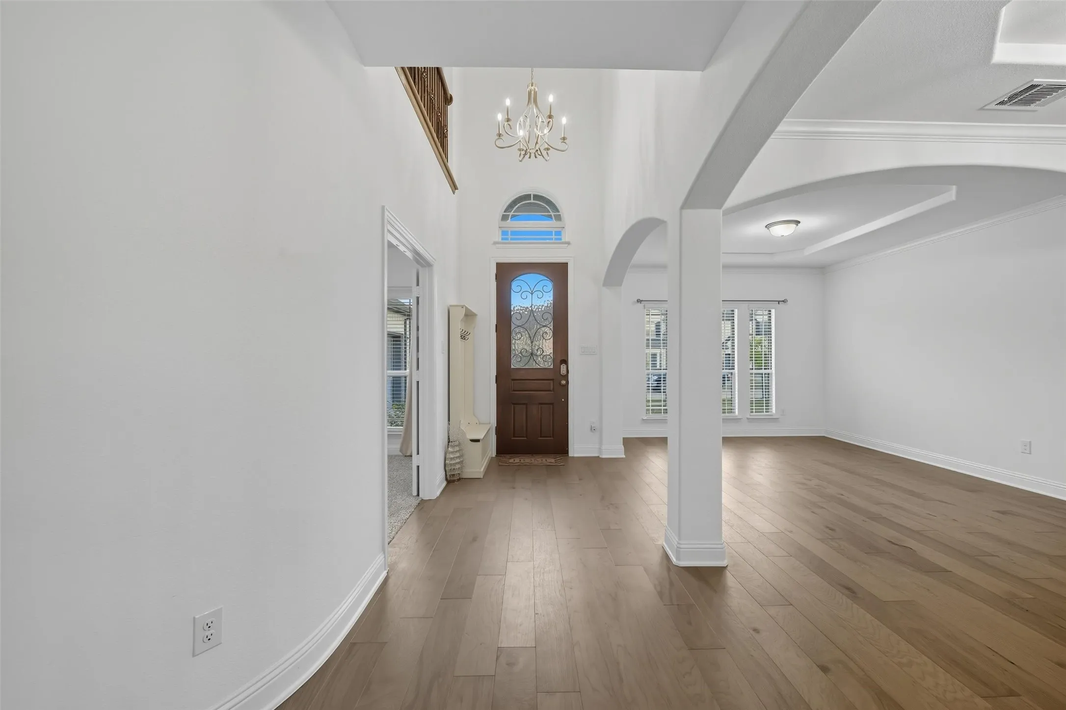 Foyer featuring a grand wood-finish entry door with decorative glass, a transom window, and a chandelier