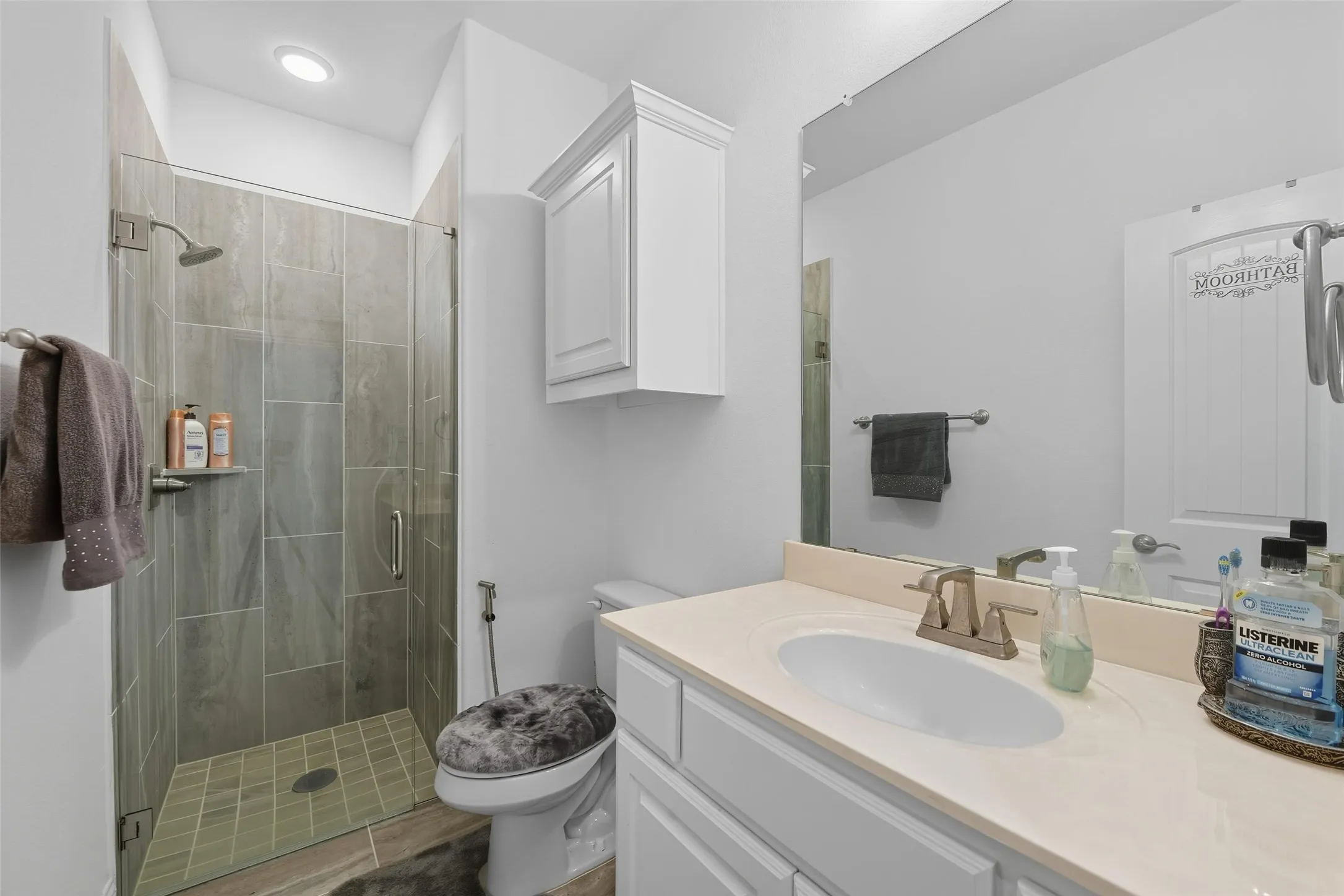 Bathroom featuring a walk-in shower with glass enclosure, wall-mounted shower head, and tiled walls