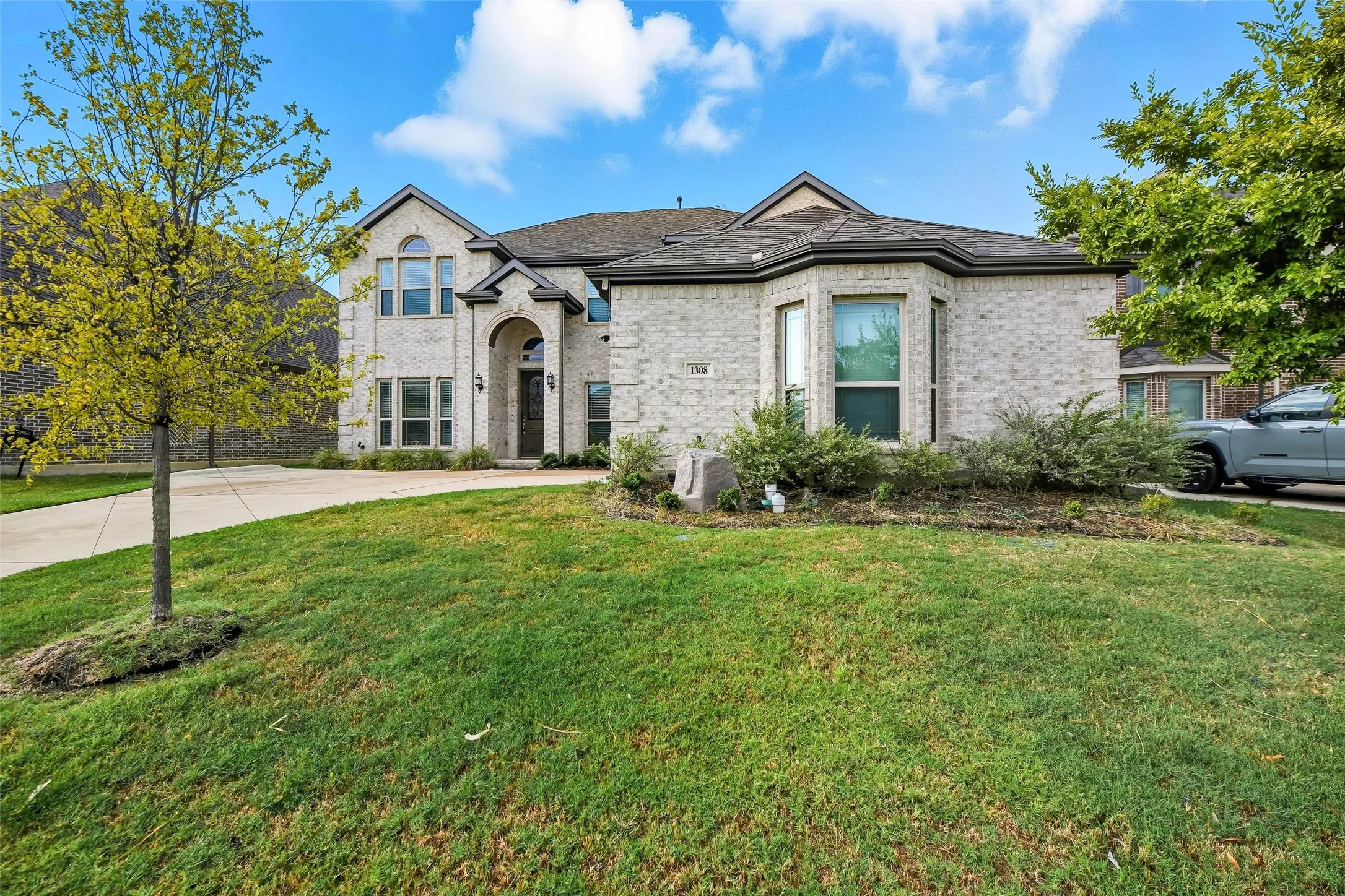Stately brick facade residence featuring a prominent arched entry, multiple gables, and a bay window