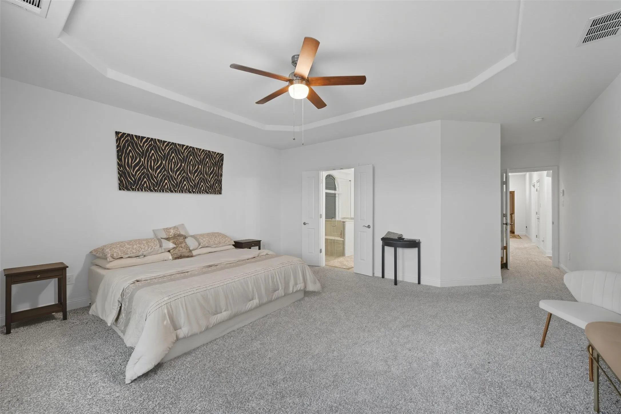 Spacious room with tray ceiling and recessed lighting, featuring light gray carpeting and white walls
