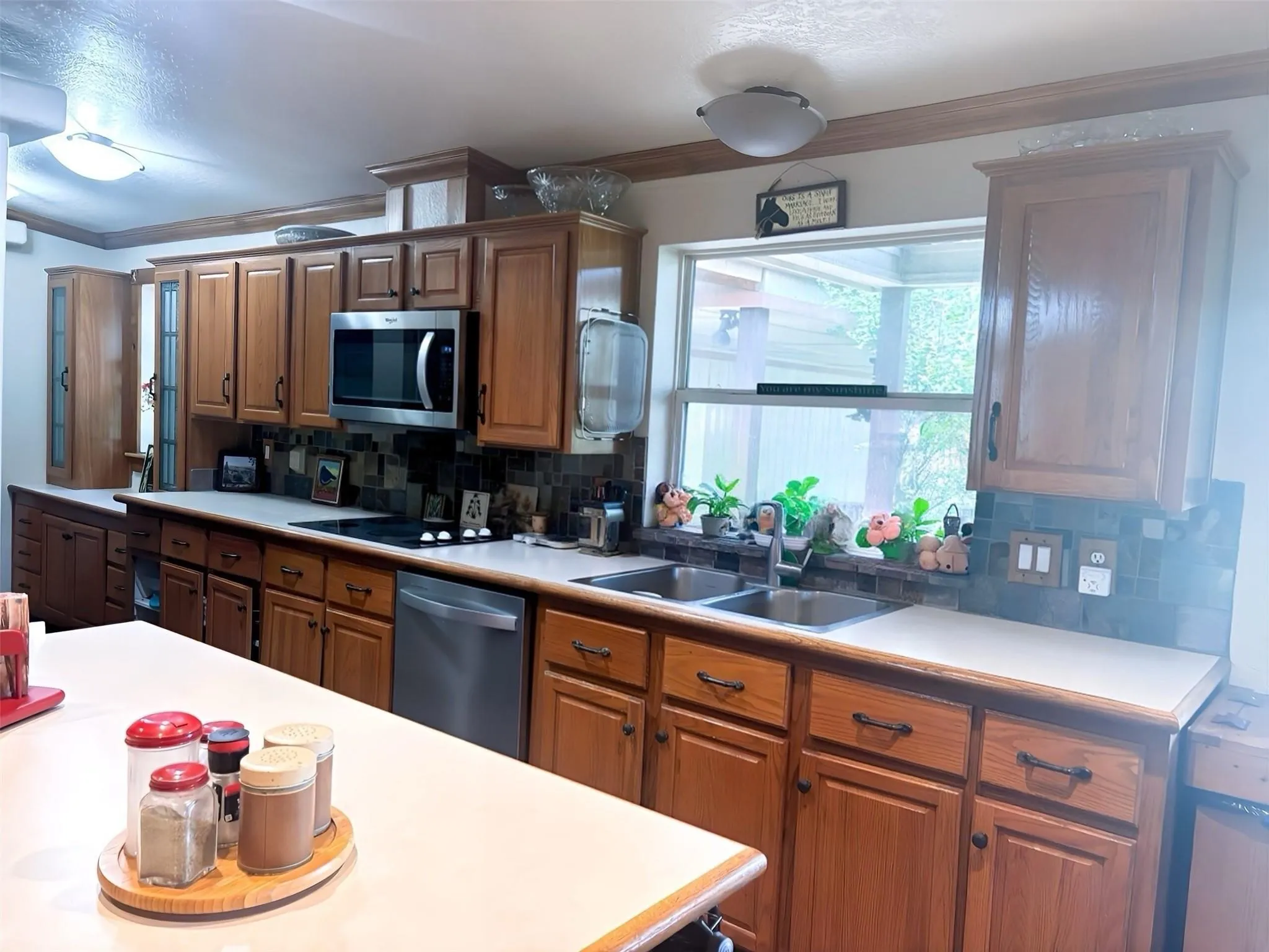 Kitchen featuring abundant wood cabinetry, an integrated stainless steel microwave, and a double basin sink