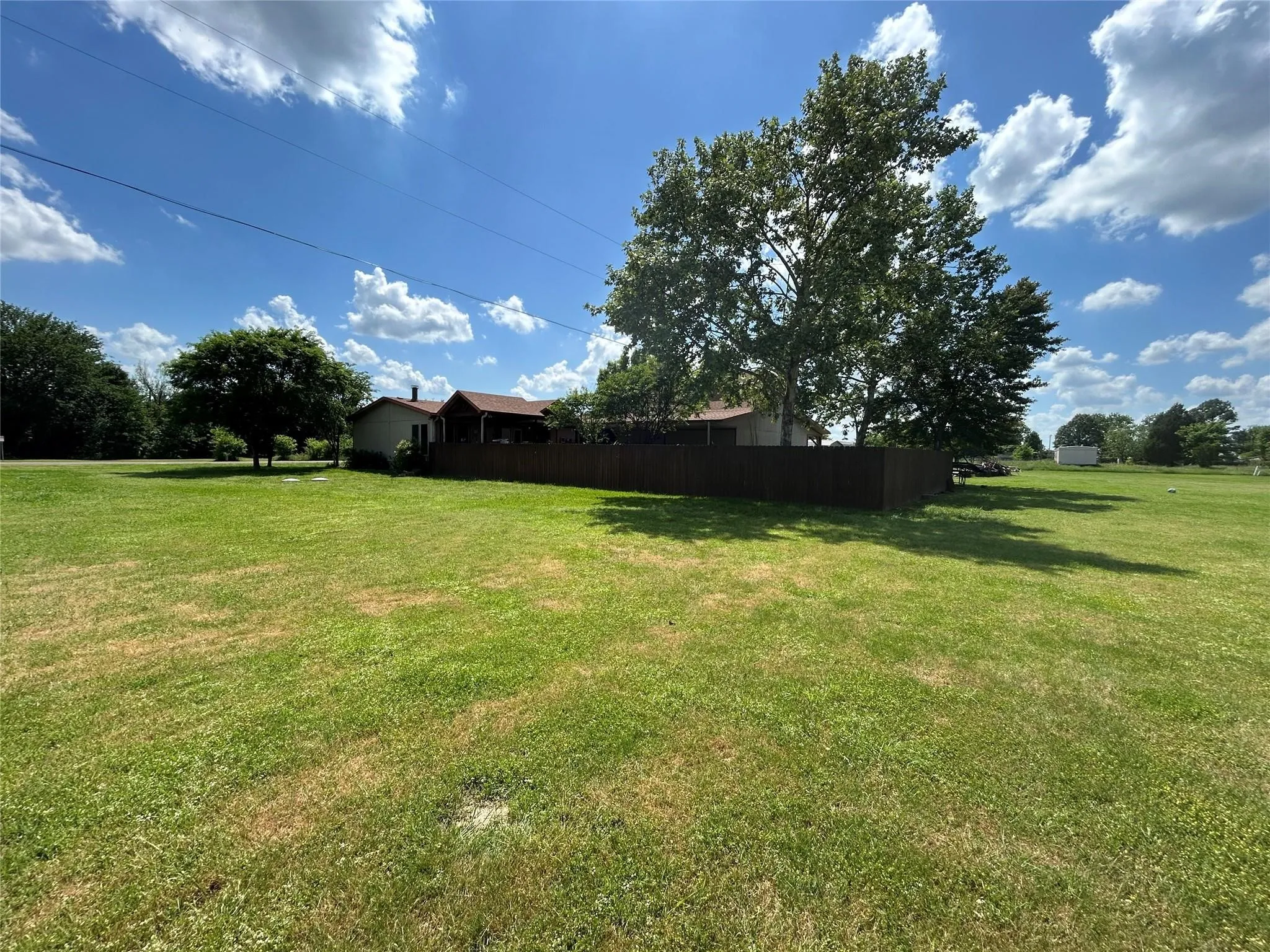 Expansive green lawn surrounding a residential structure with a brown privacy fence