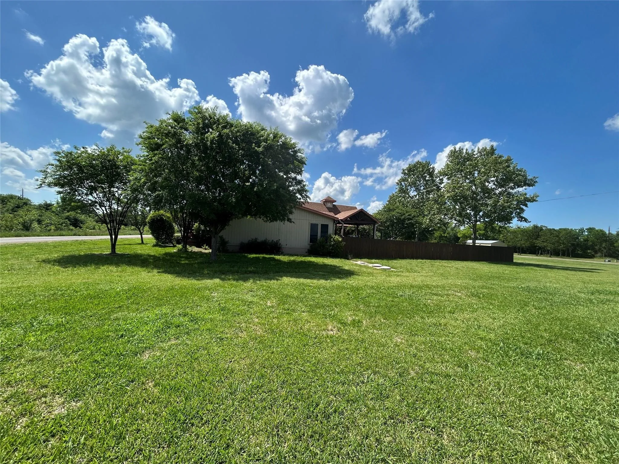 Expansive green lawn with mature trees providing shade