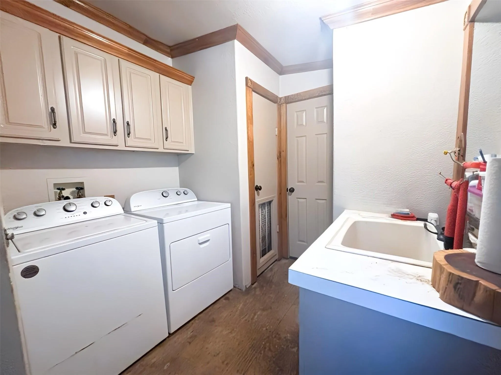 Dedicated utility space featuring wood-finish flooring, white walls, and wood trim accents