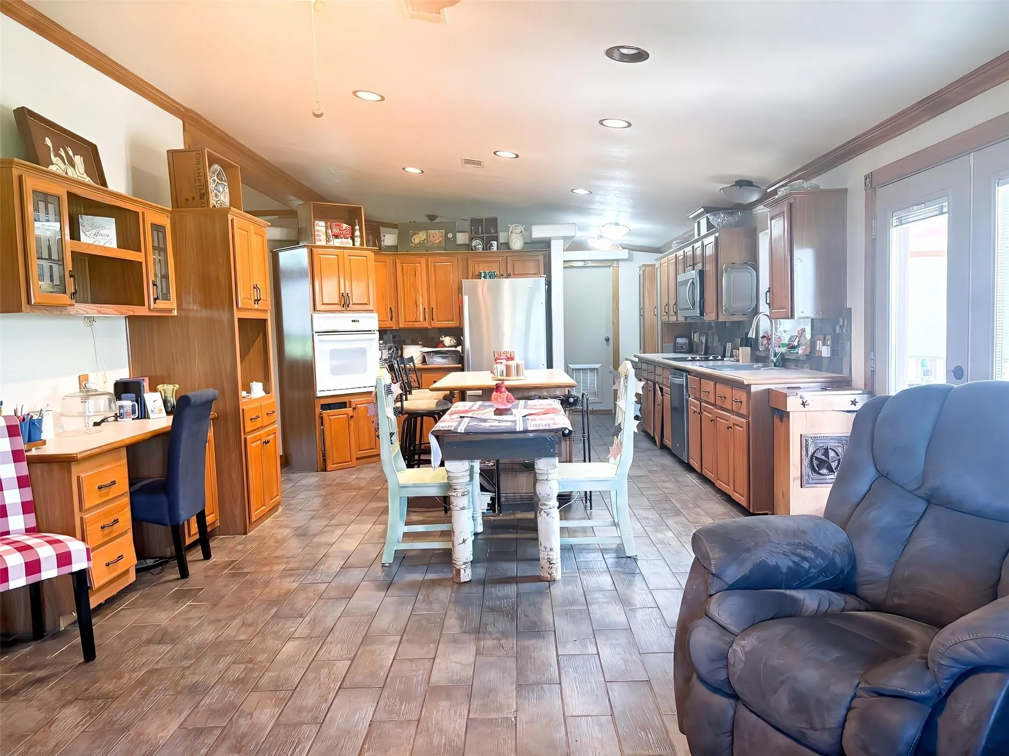 Open-concept kitchen featuring extensive wood cabinetry, tile flooring, recessed lighting, double French doors, and built-in appliances