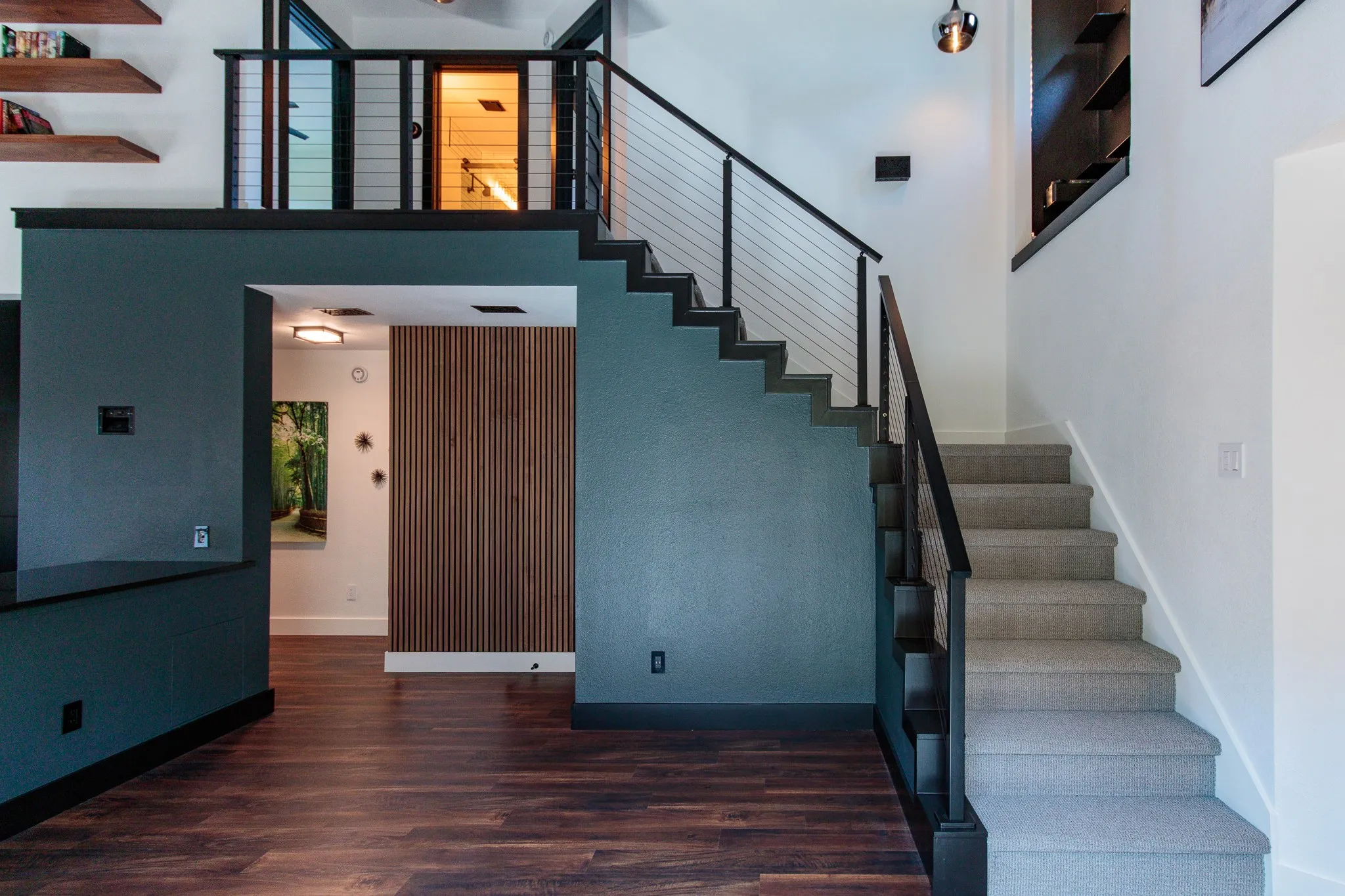 Modern interior featuring wood-finish flooring, a carpeted staircase with a metal cable railing, and a loft with a matching railing