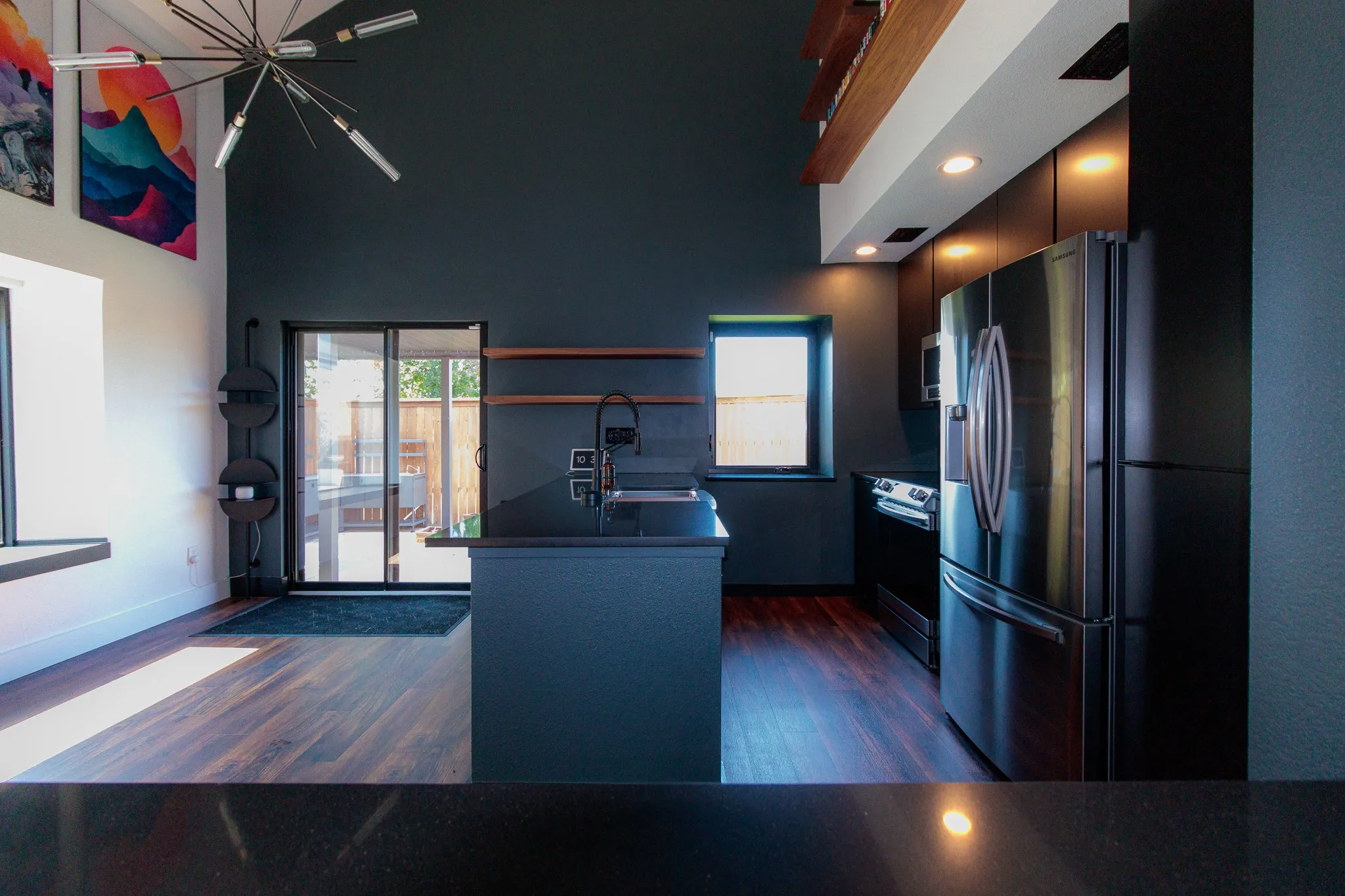 Modern kitchen featuring dark cabinetry, stainless steel appliances, and wood-finish flooring