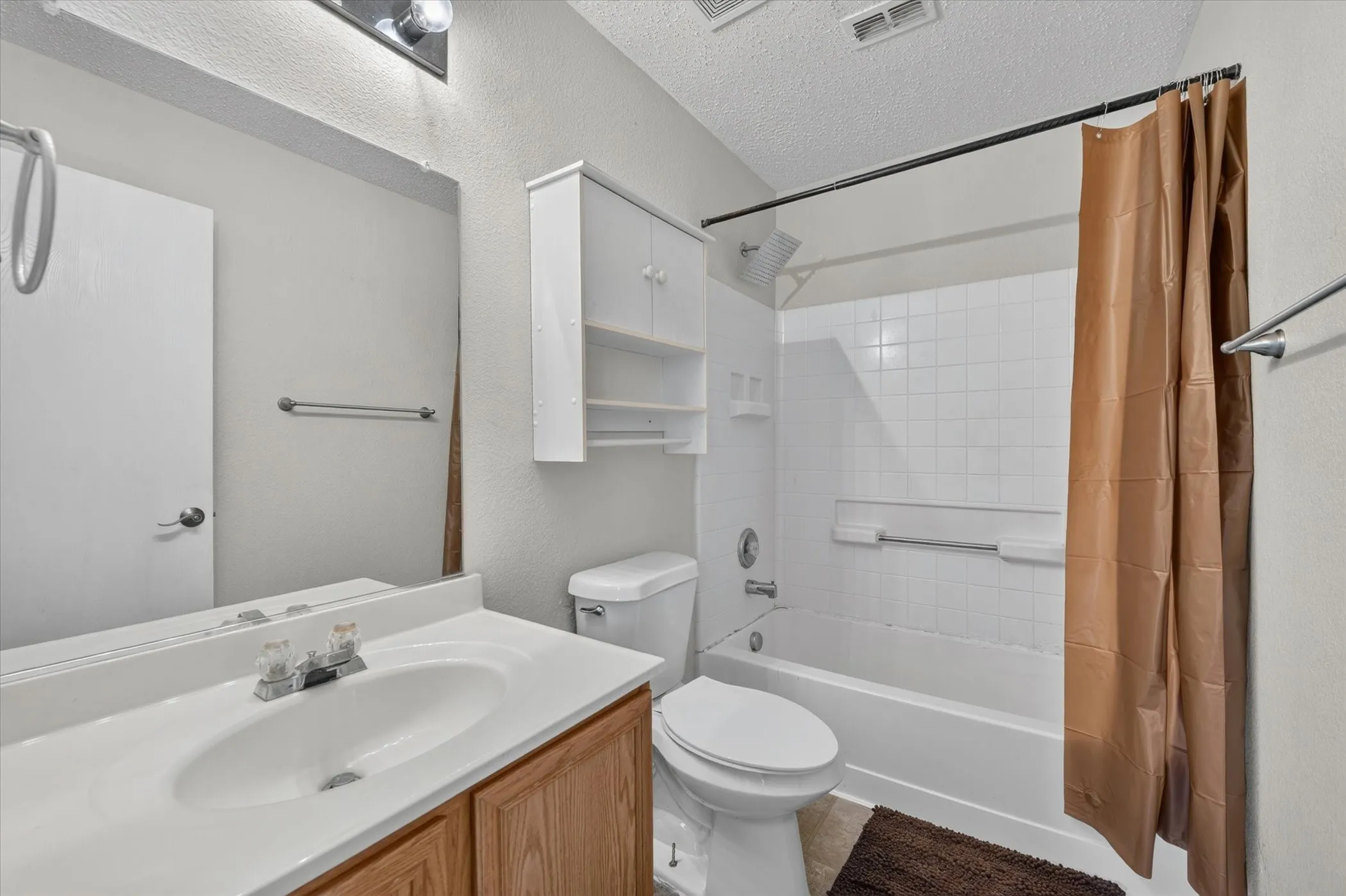 Full bathroom featuring a single vanity with wood-finish cabinetry, a white countertop, and an integrated sink