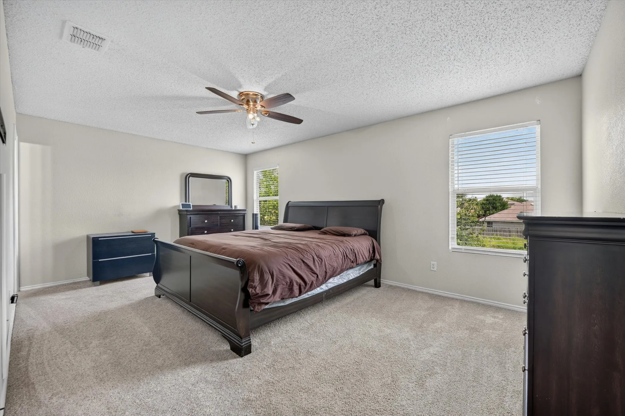 Spacious carpeted room featuring light beige walls and a textured ceiling