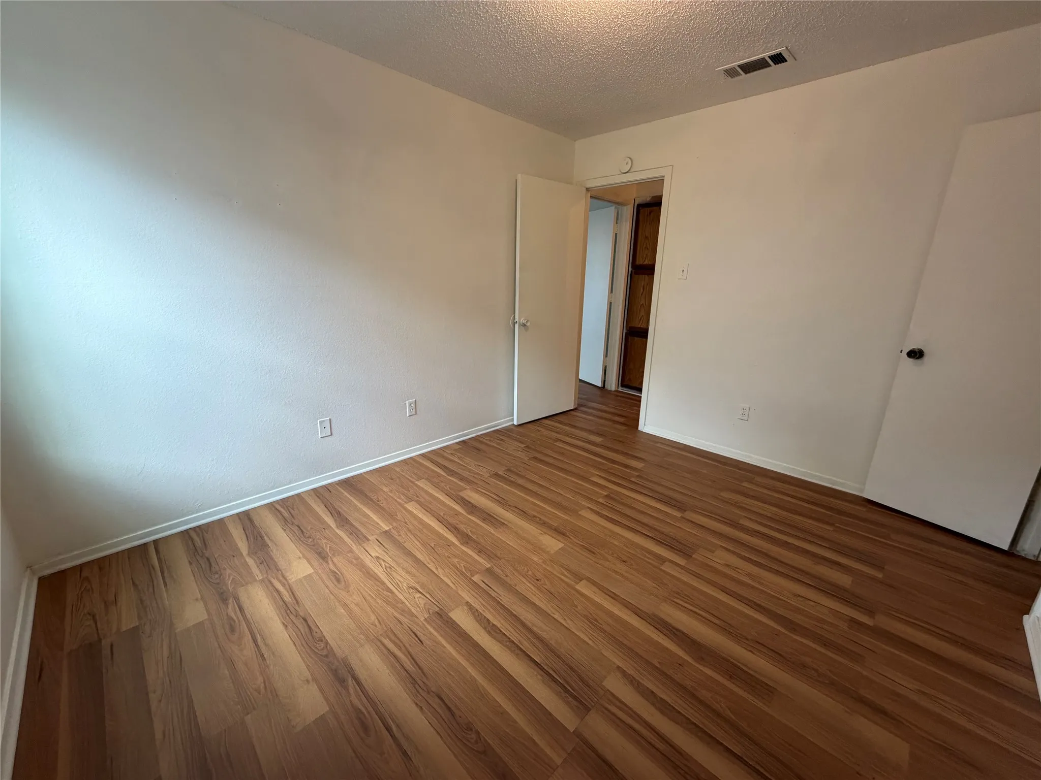 Room featuring wood-finish flooring, white baseboards, and white walls