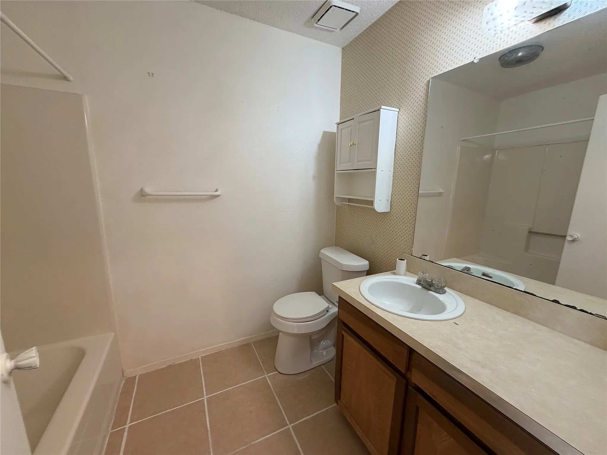 Bathroom featuring a full vanity with wood-finish cabinetry, a built-in sink, and an expansive wall-mounted mirror