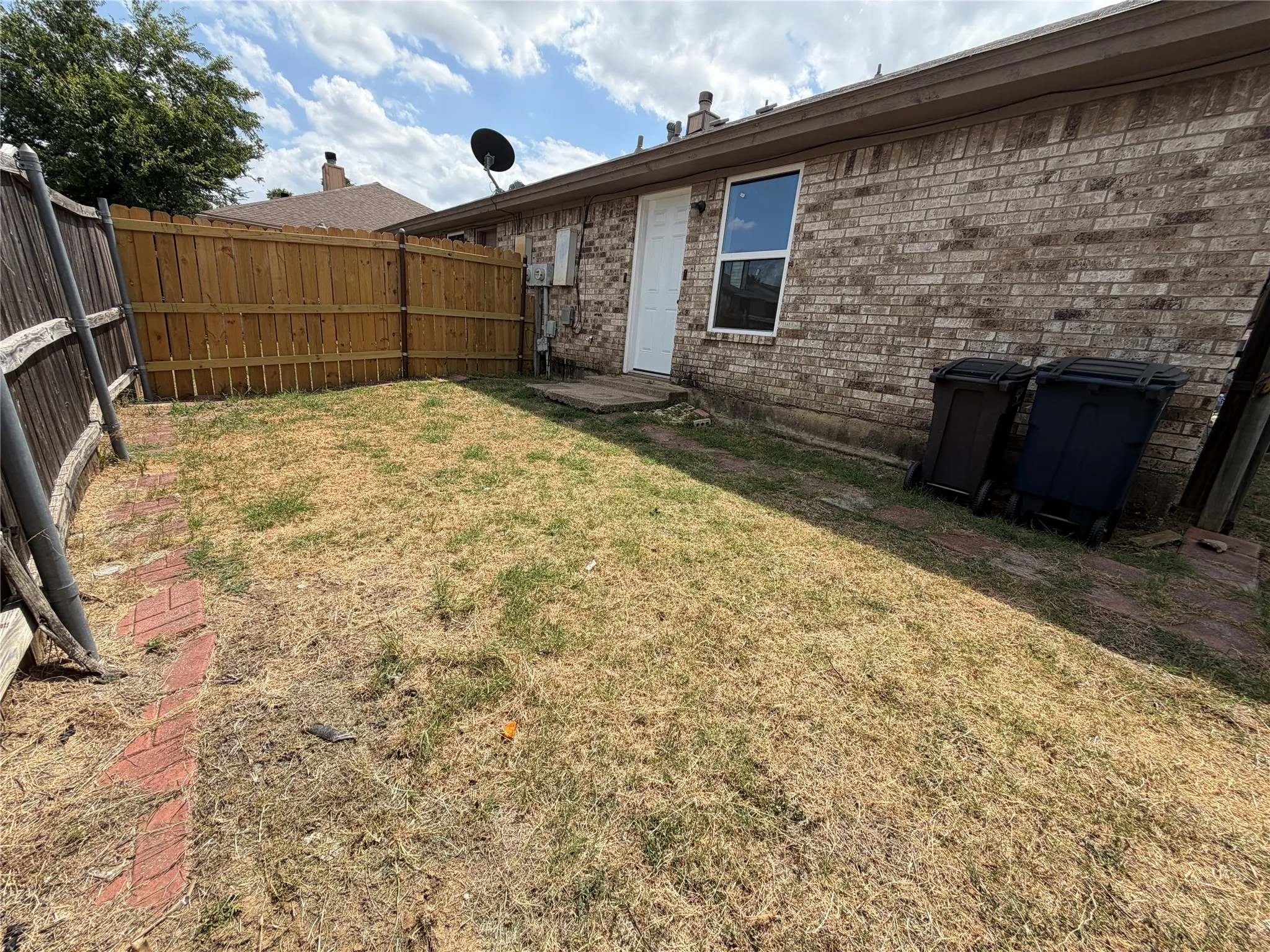 Enclosed backyard featuring a wood privacy fence and a brick exterior
