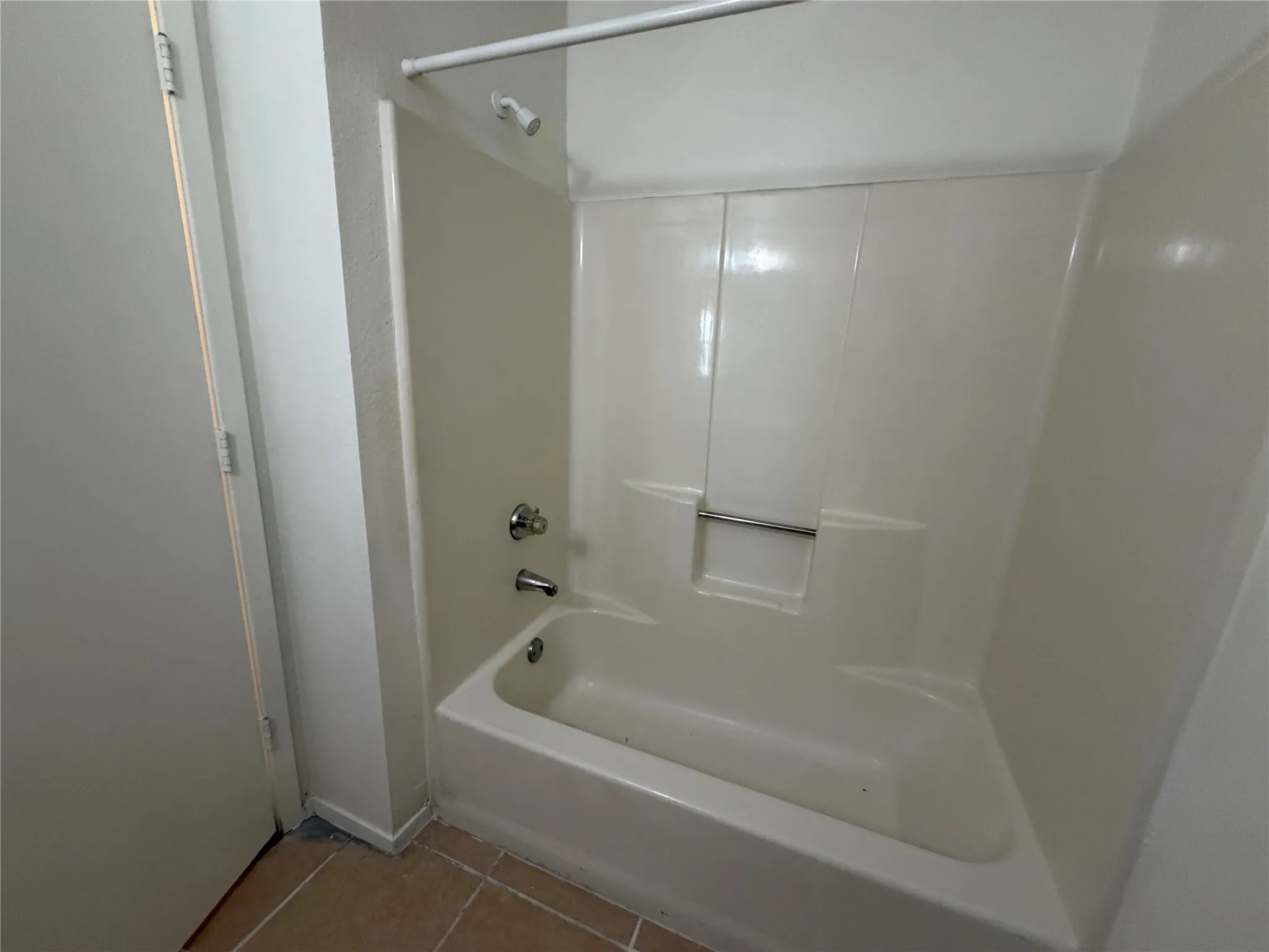 White fiberglass tub and shower combination with chrome fixtures and shower rod