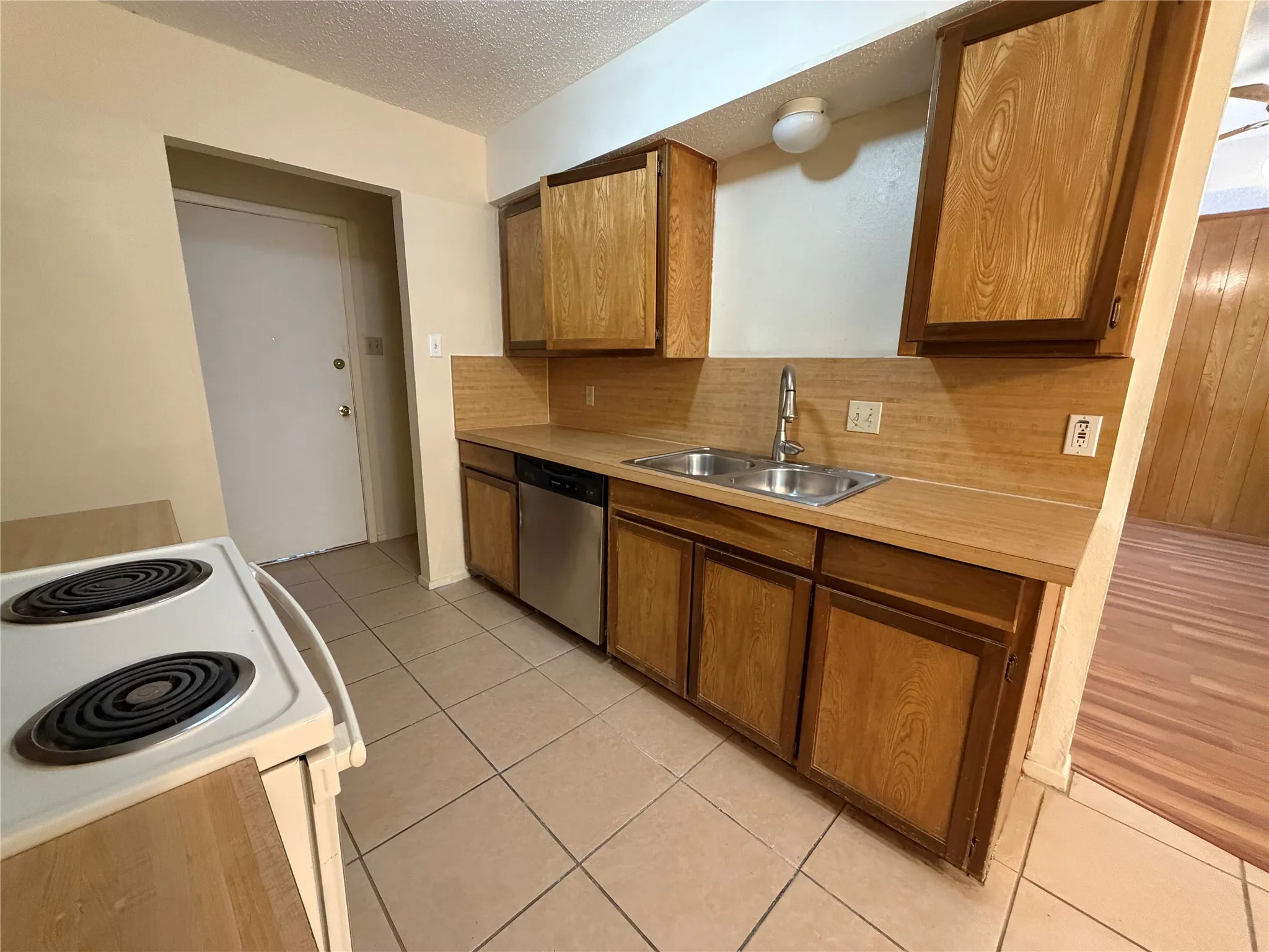 Kitchen featuring wood cabinetry, laminate countertops, a double-basin stainless steel sink, and a stainless steel dishwasher