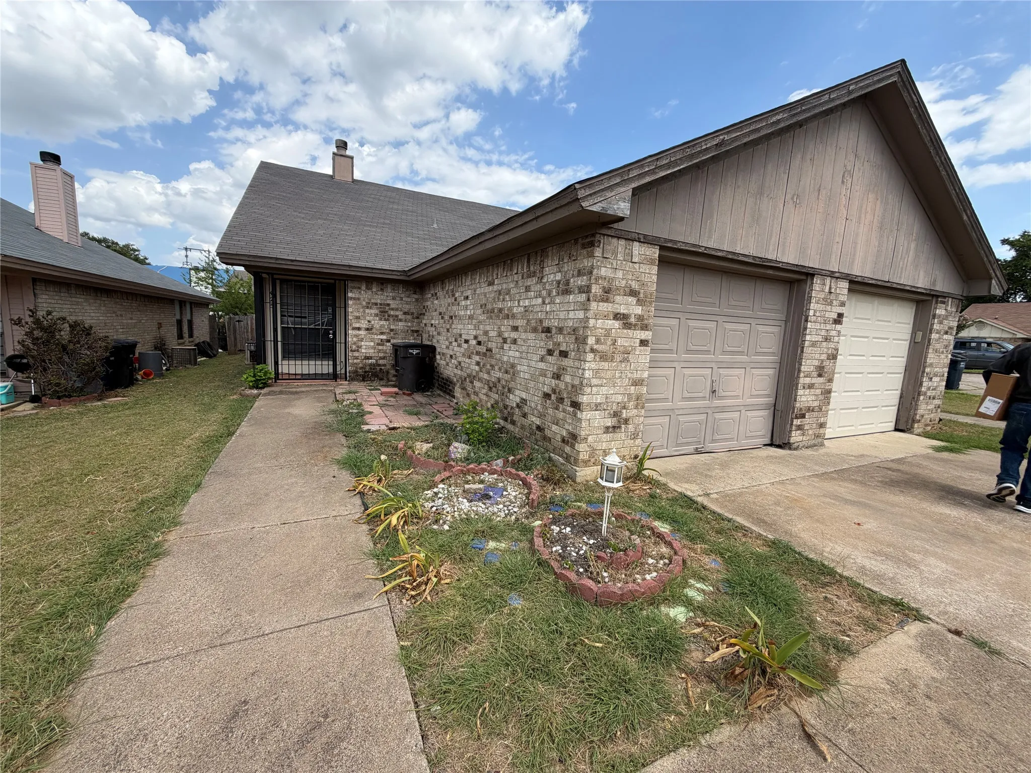 Brick exterior featuring a two-car garage with individual doors, a fenced entry, and a concrete walkway