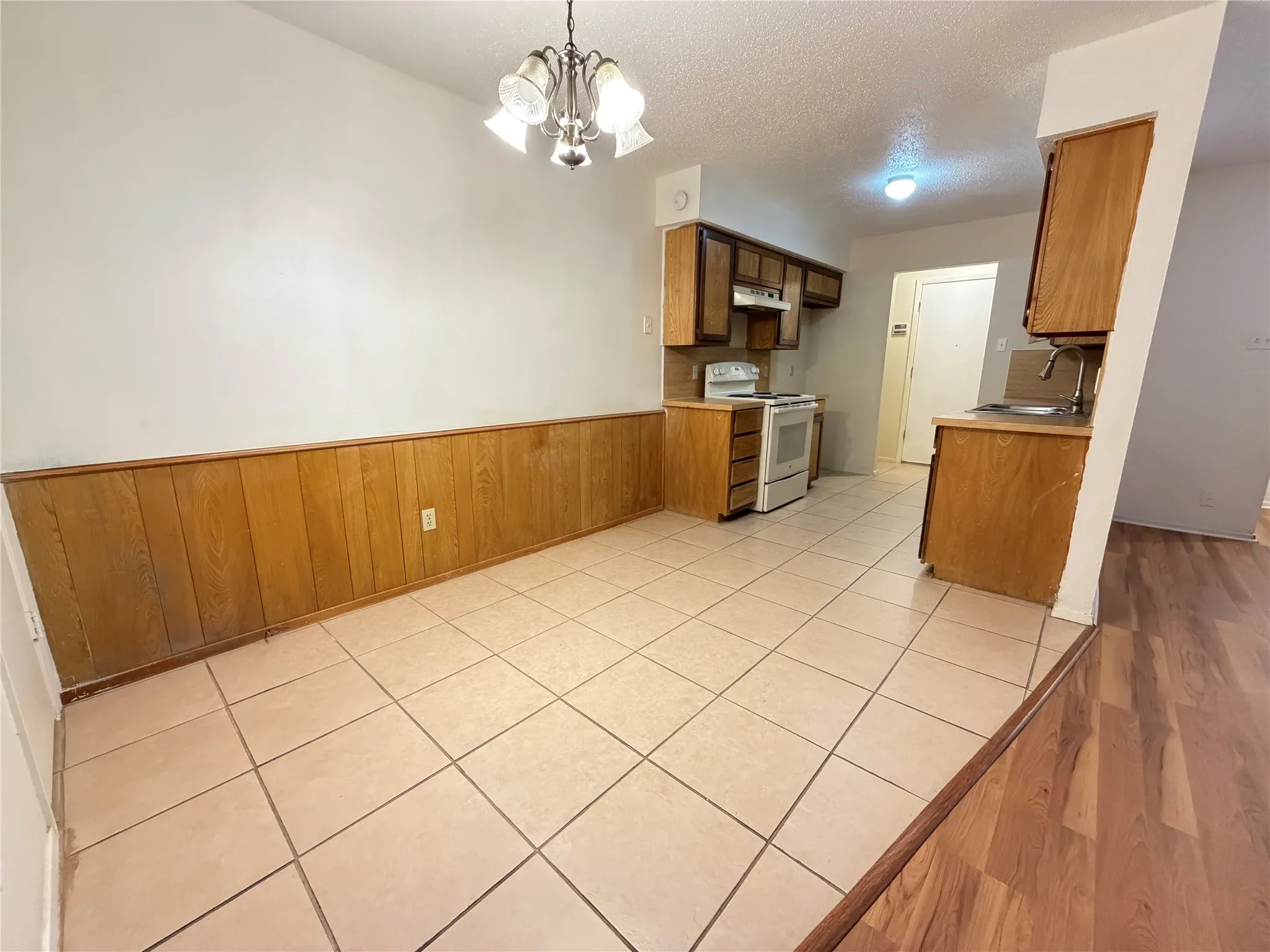 Dining area featuring wood paneling, tile flooring, and a decorative chandelier