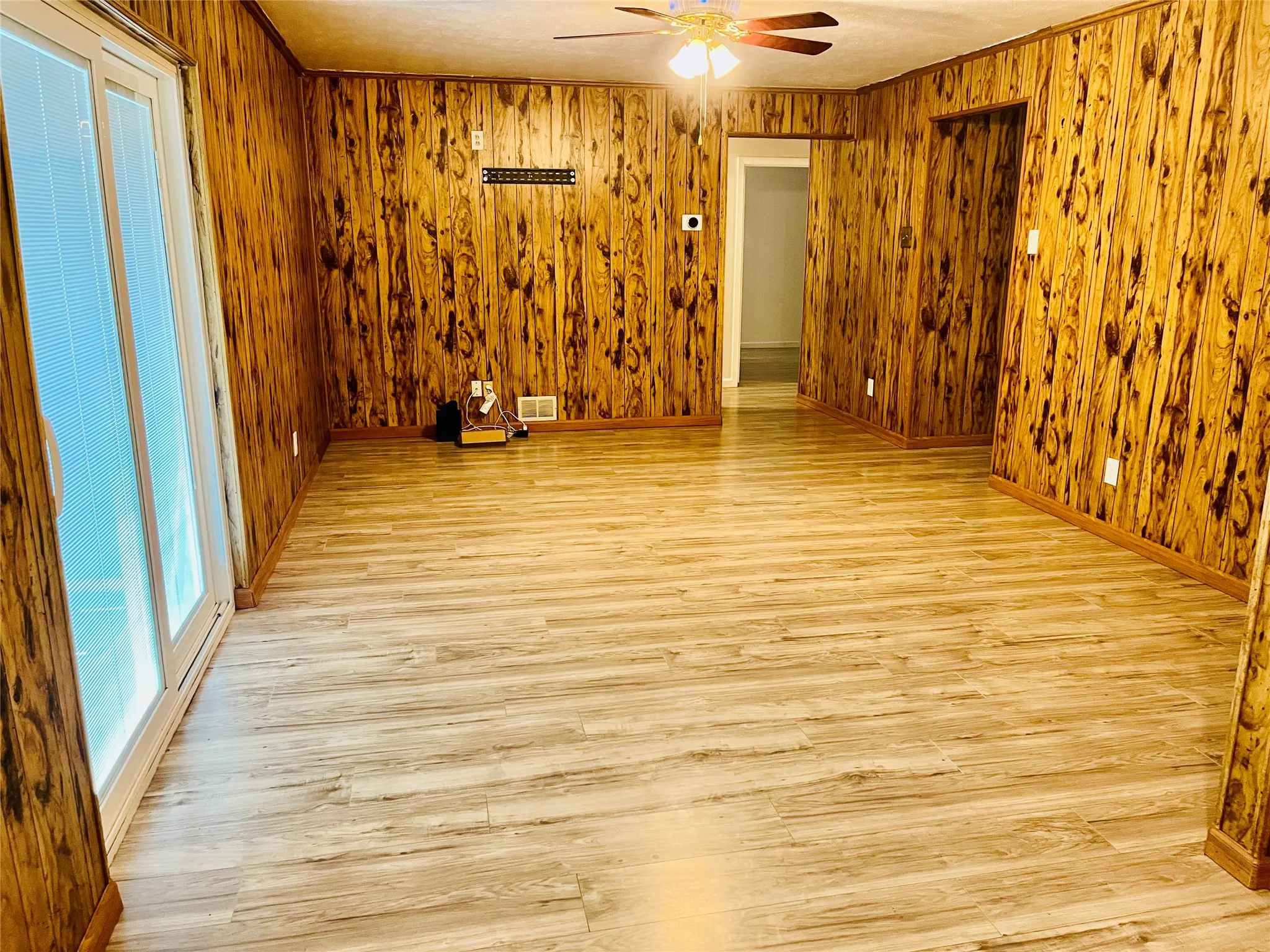 Spacious room featuring wood paneling, wood-finish flooring, and white trim