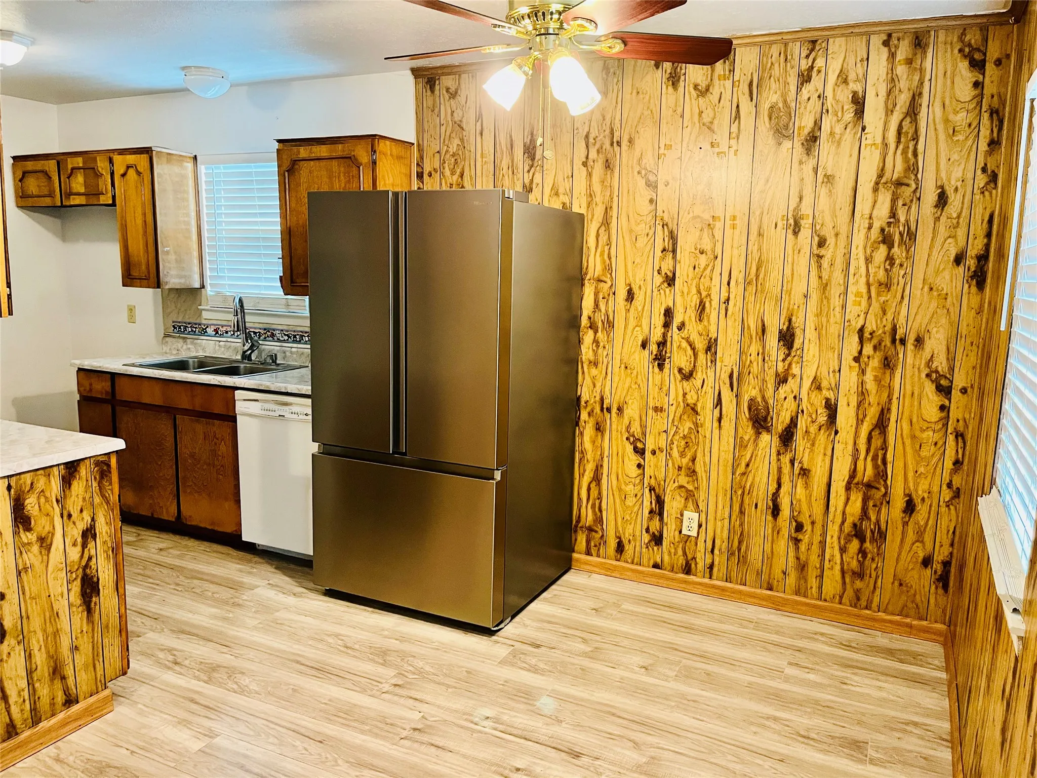Kitchen space featuring wood-finish wall paneling, light wood-finish flooring, and a stainless steel refrigerator
