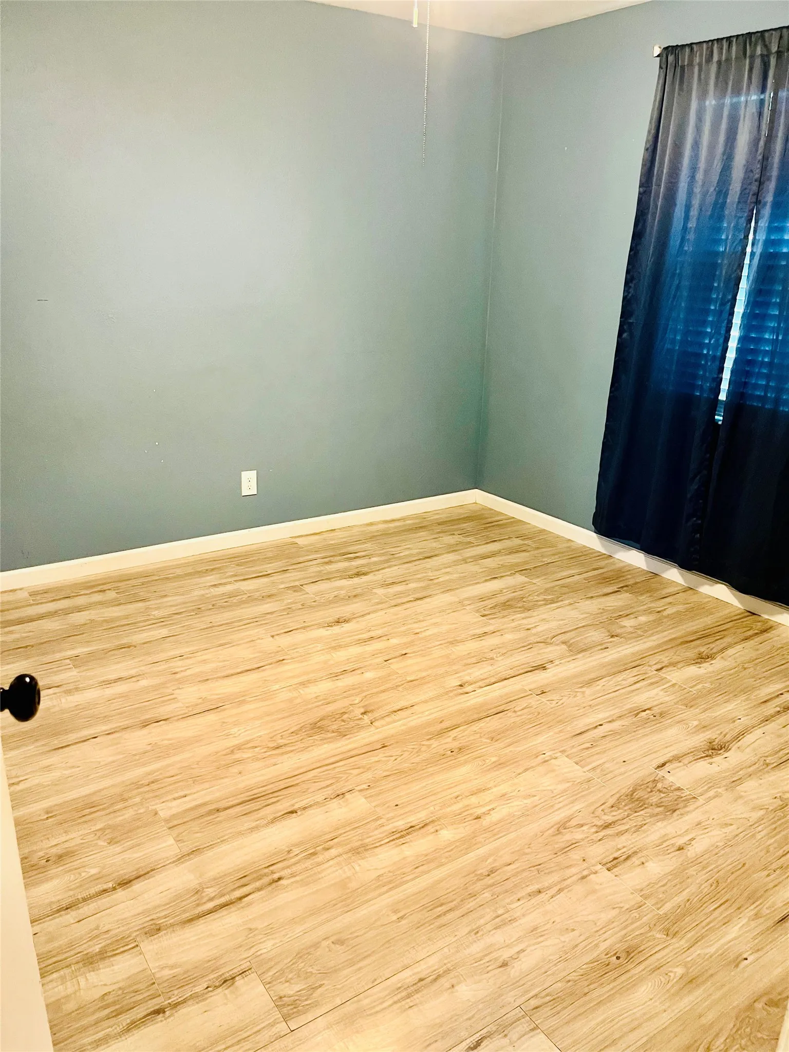 Wood-finish flooring with light wood tones and a white baseboard trim