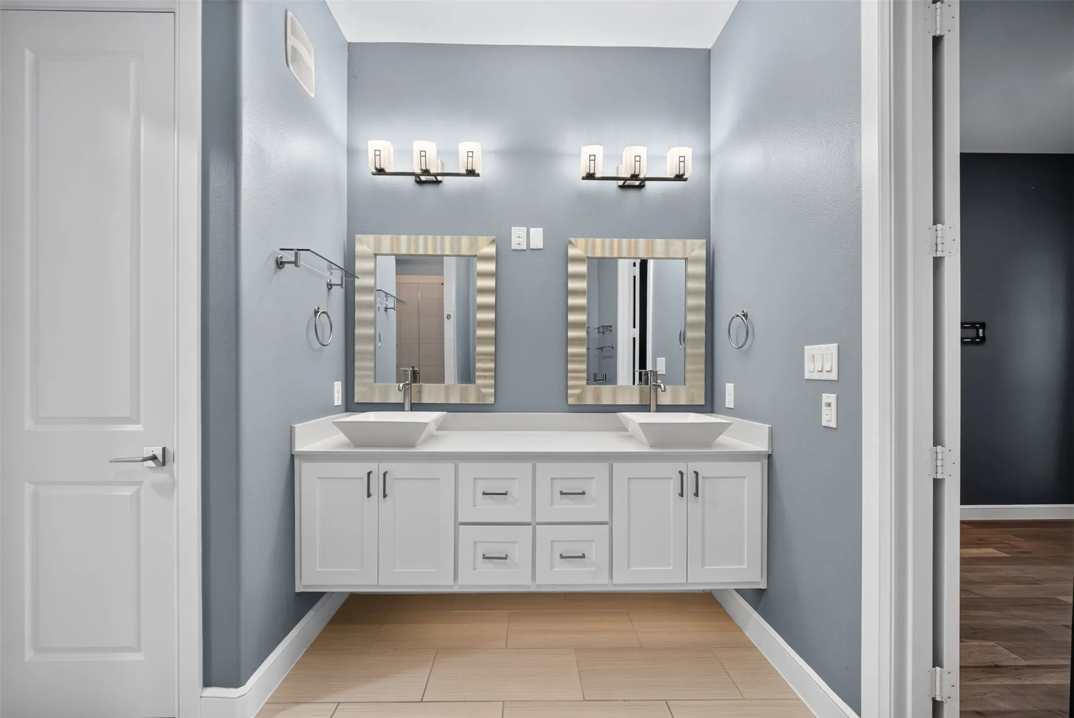 Dual vessel sinks set on a floating white vanity with brushed nickel hardware