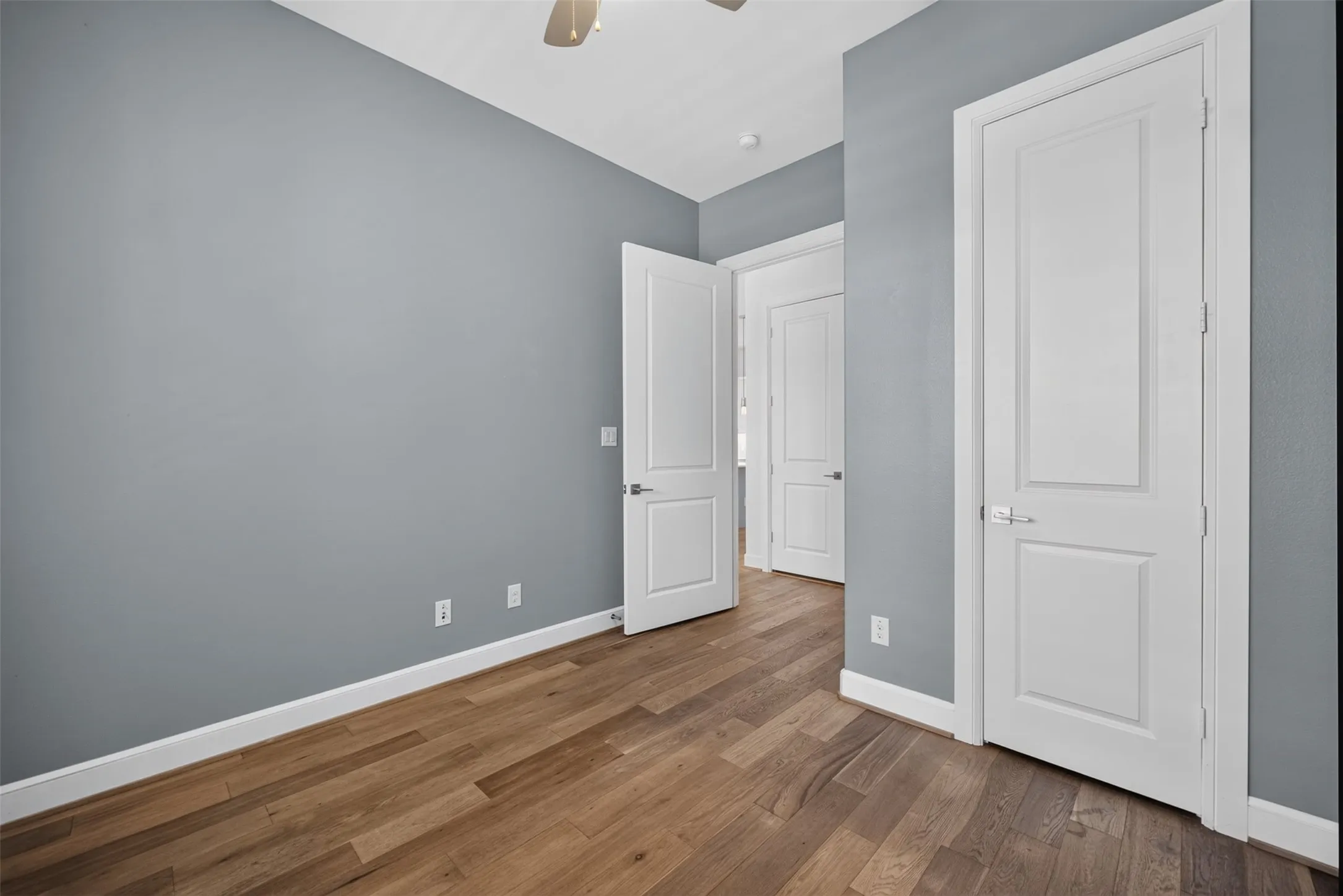 Interior room featuring wood-finish flooring, light gray wall paint, and white baseboards