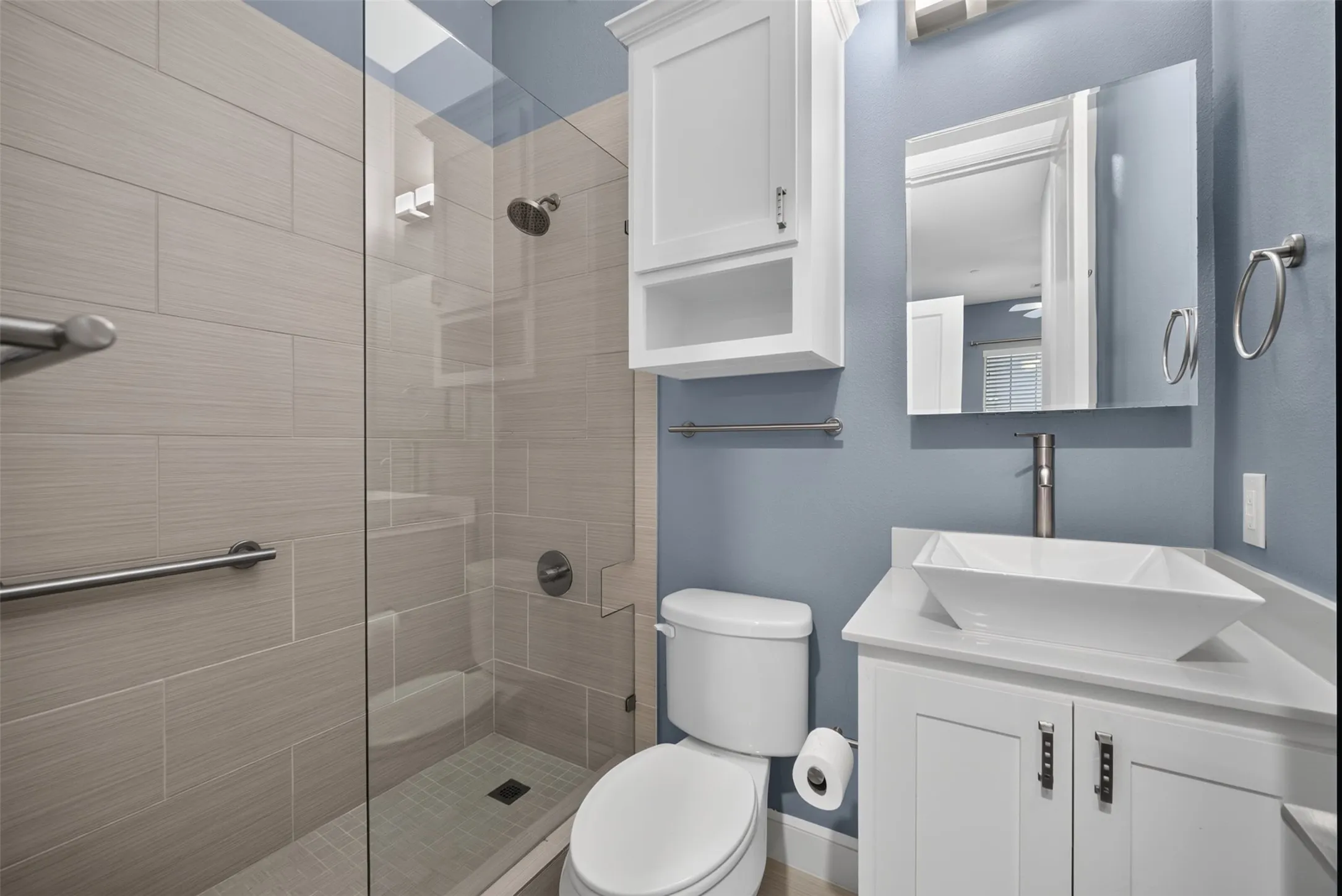 Contemporary bathroom featuring a glass-enclosed shower with tile surround and integrated grab bars
