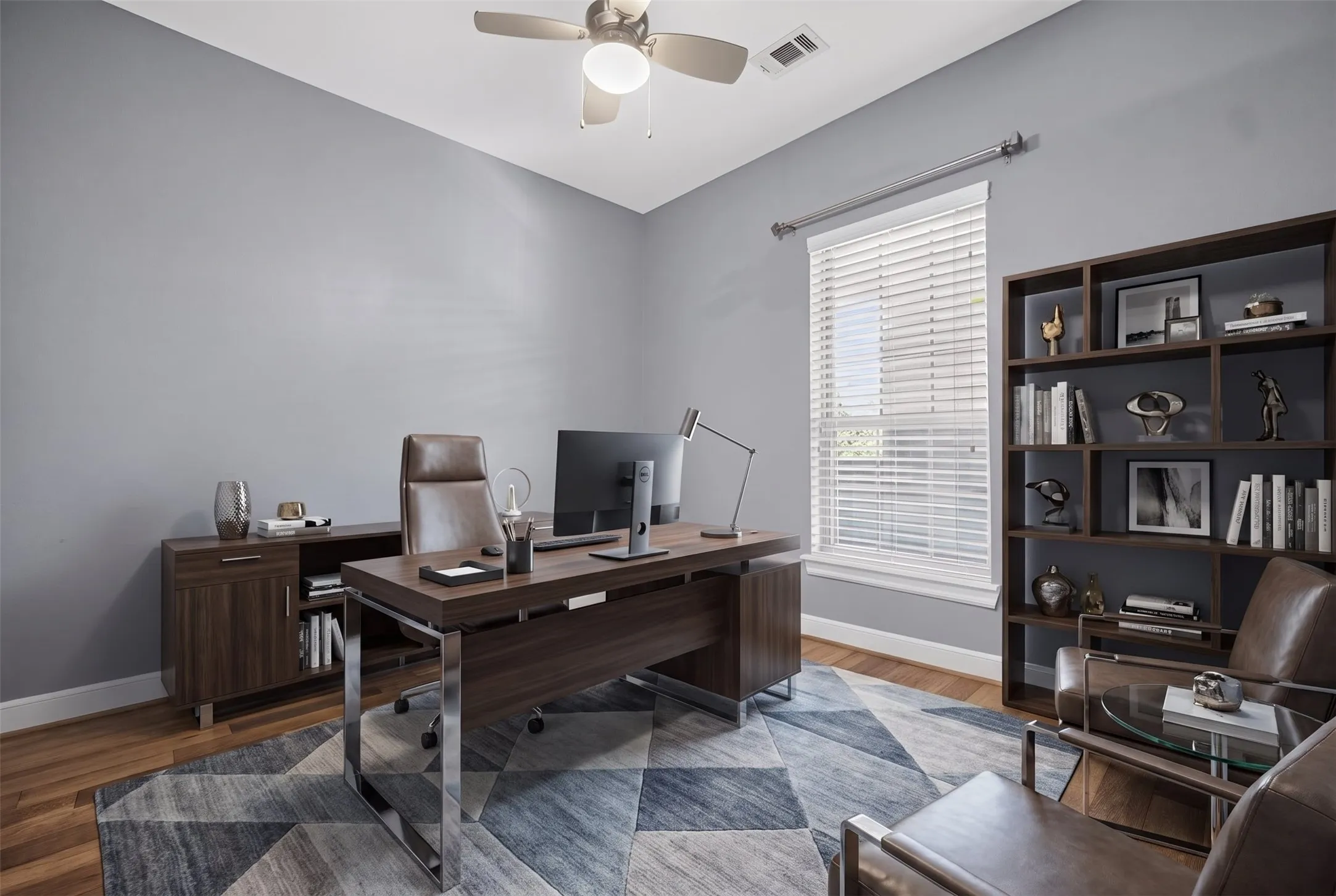 Bright room with a ceiling fan, light gray walls, wood-finish flooring, and a large window with white blinds
