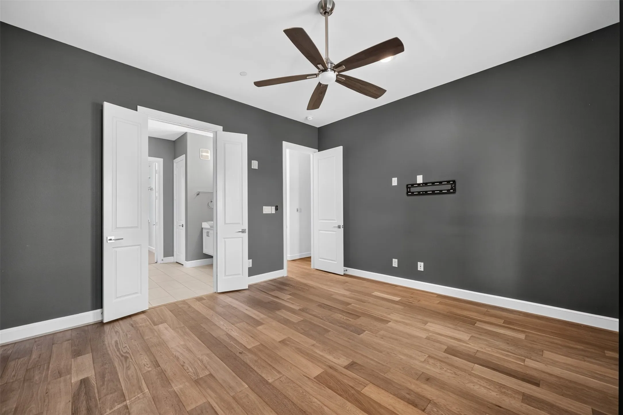 Spacious room featuring wood-finish flooring and dark gray walls