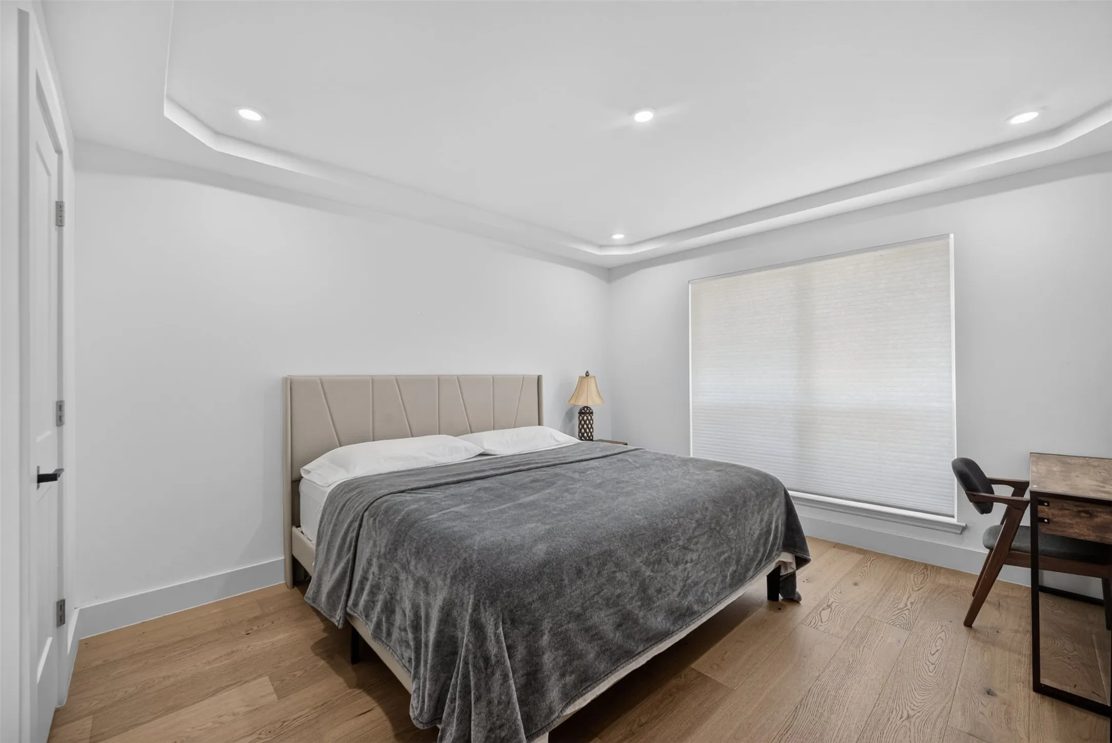 Spacious room featuring wood-finish flooring, a recessed ceiling with cove lighting, and recessed can lighting