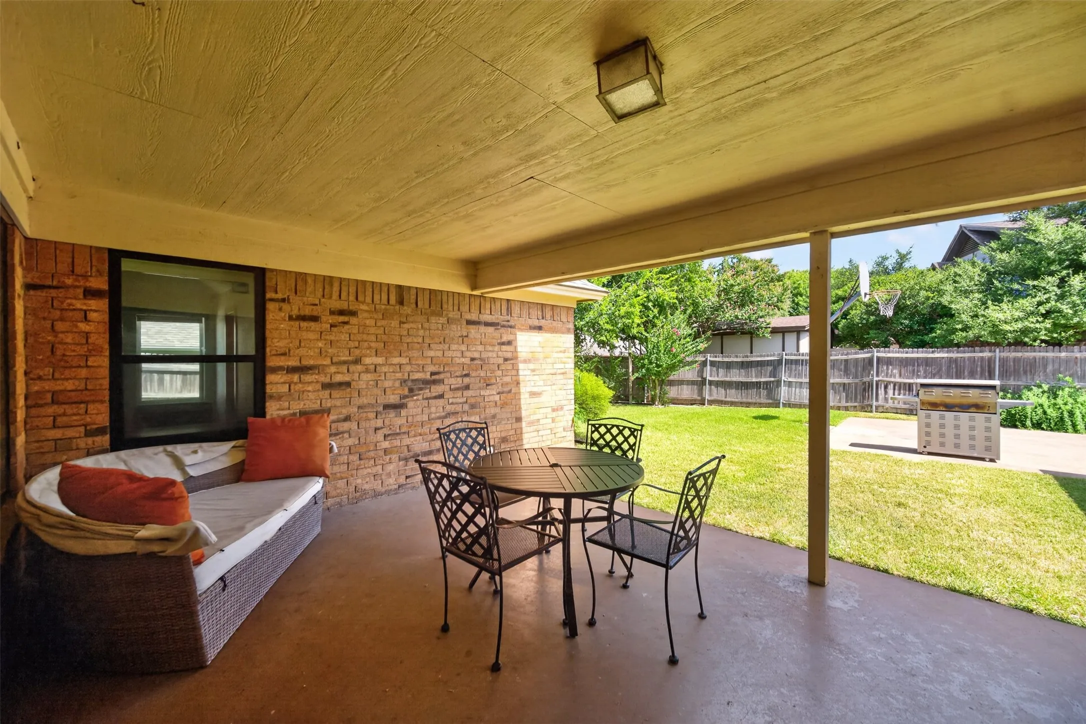 Covered patio featuring a brick exterior wall, a fixed window, and a concrete surface