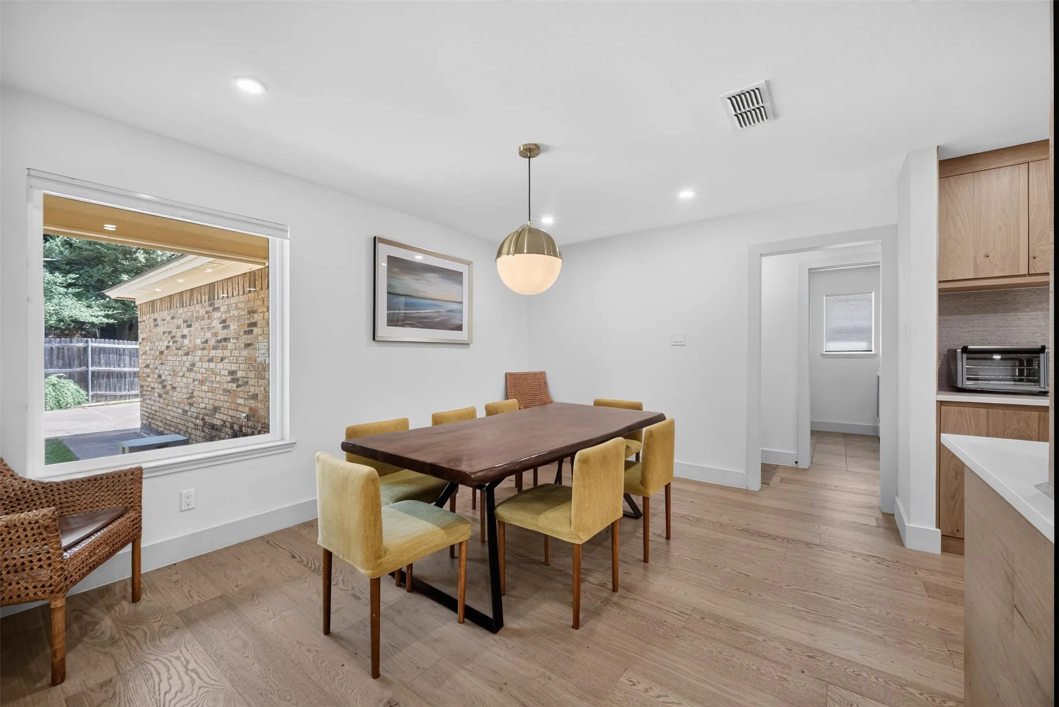 Spacious dining area featuring wood-finish flooring, recessed lighting, and a modern spherical pendant light