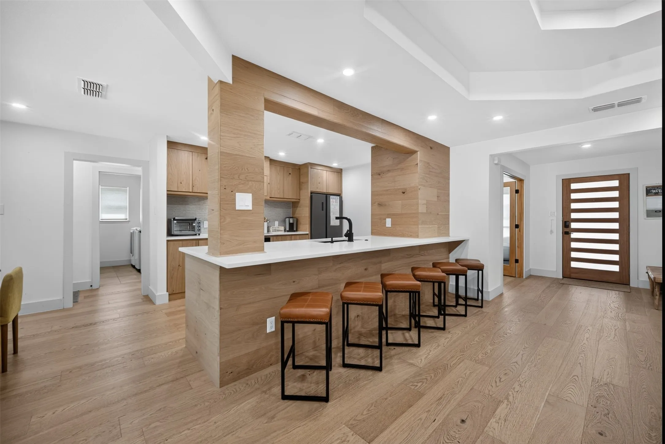Modern kitchen featuring a wood-finish peninsula with a white countertop and integrated sink