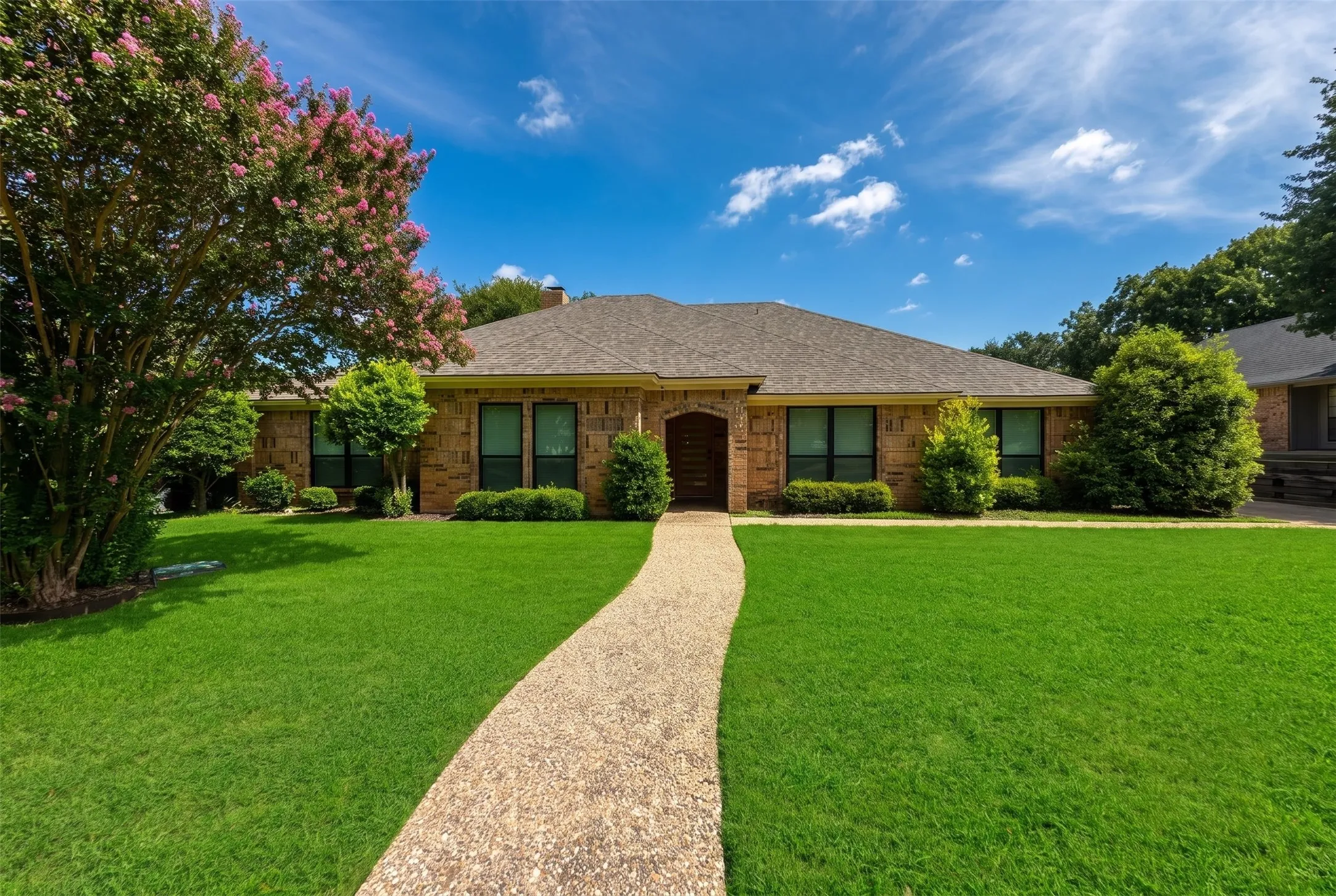 Brick facade residence featuring a front gabled roof and arched entryway