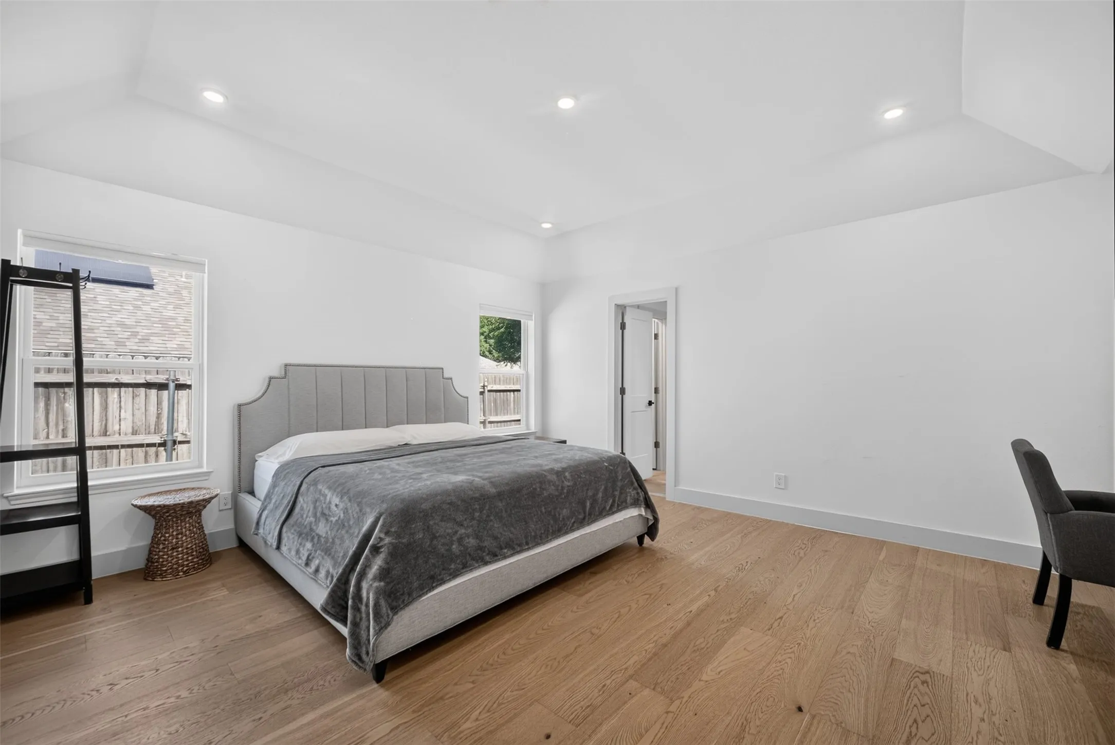 Spacious room featuring wood-finish flooring, white walls, and recessed lighting