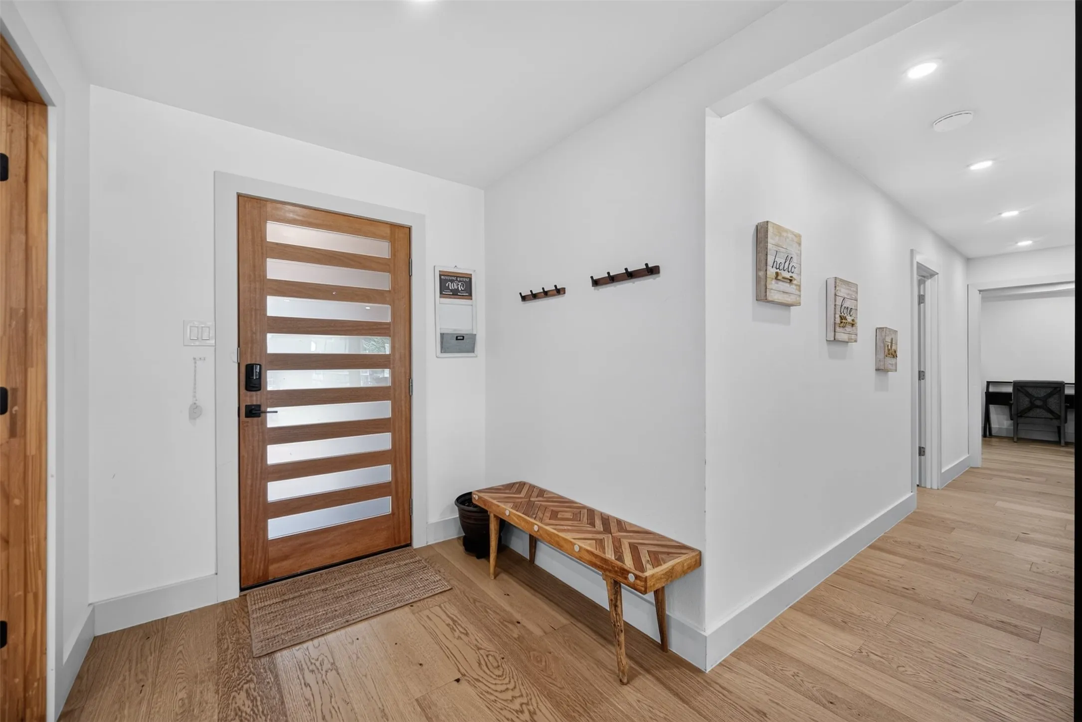 Contemporary entry featuring a wood door with horizontal glass inserts, light wood-finish flooring, recessed lighting, and white baseboards