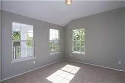 Unfurnished room featuring vaulted ceiling and carpet flooring