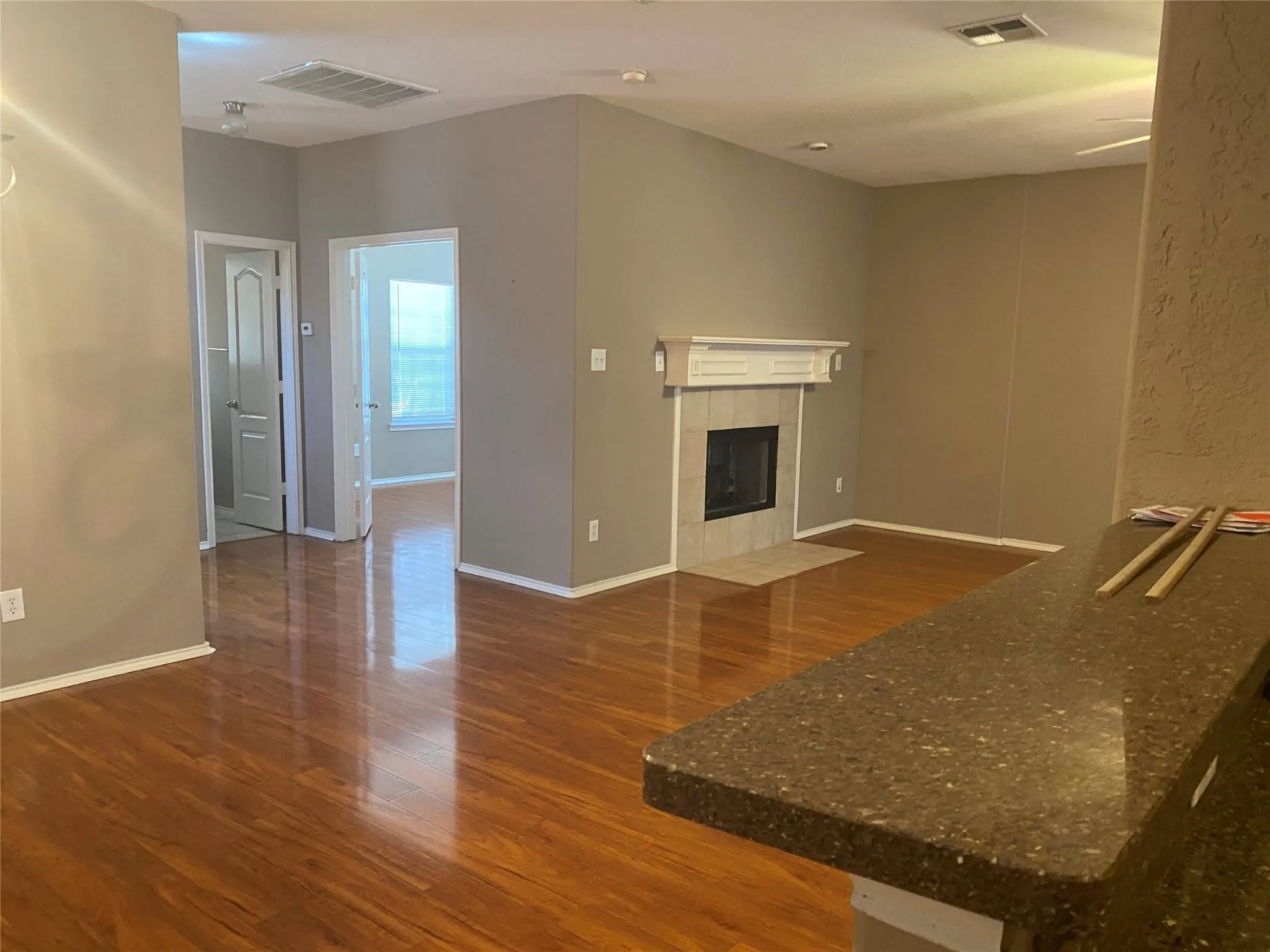 Unfurnished living room with wood finished floors and a tiled fireplace