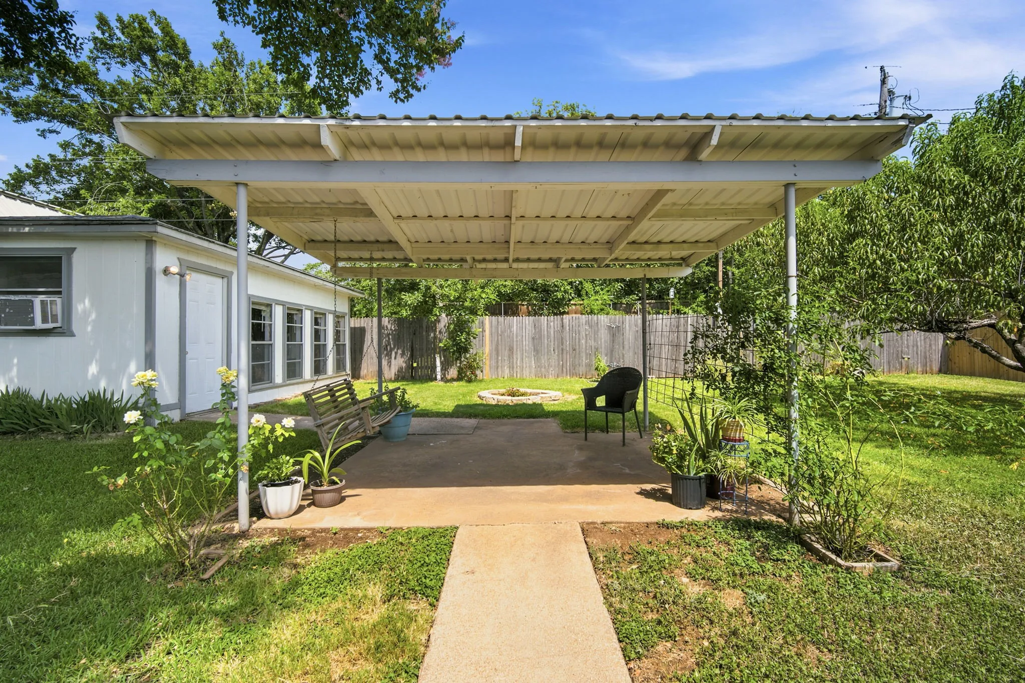 Covered patio featuring a ceiling fan, concrete flooring, and brick half-walls