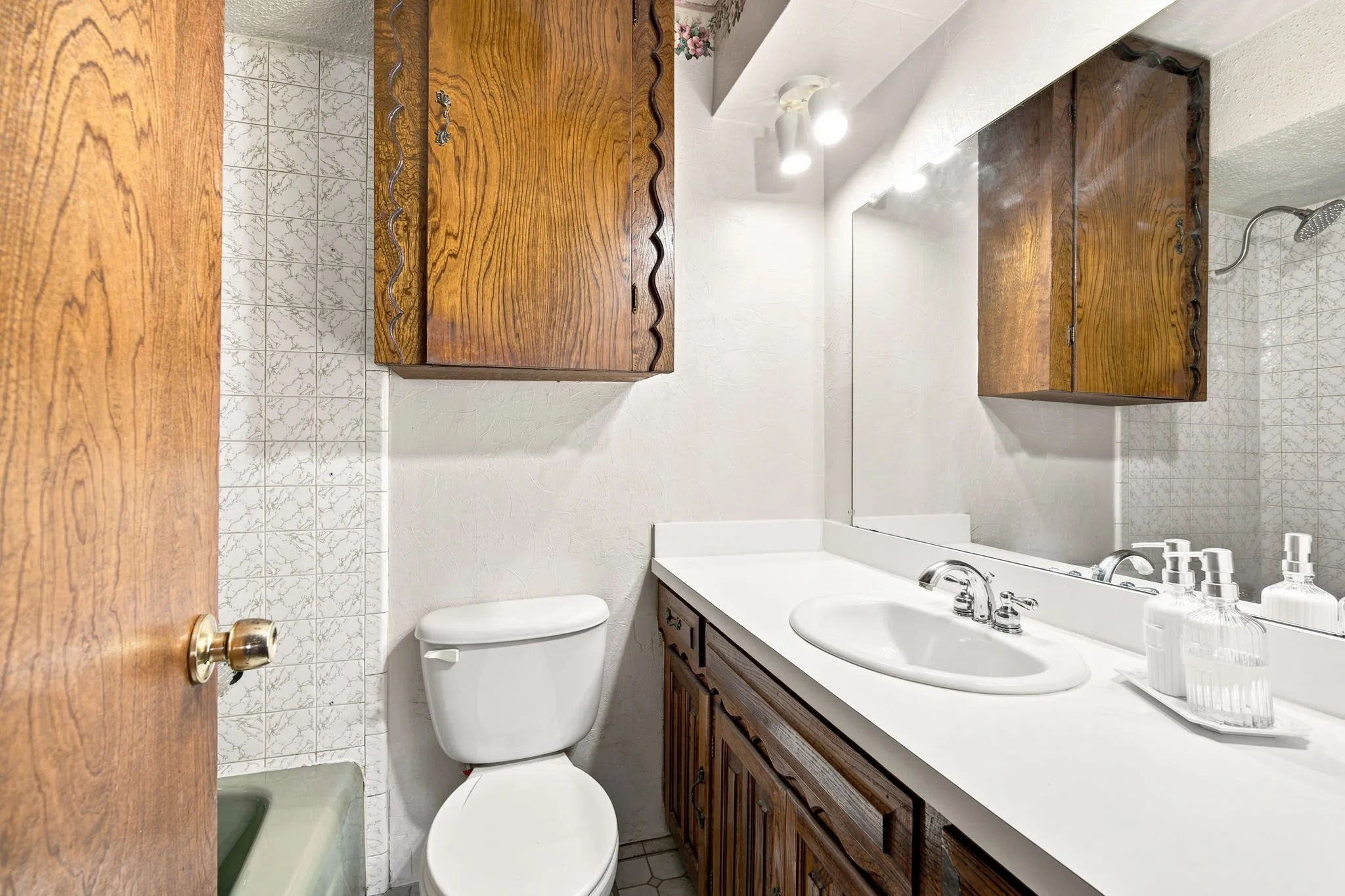 Bathroom featuring a white vanity countertop, integrated sink, chrome faucet, and wood-finish cabinetry