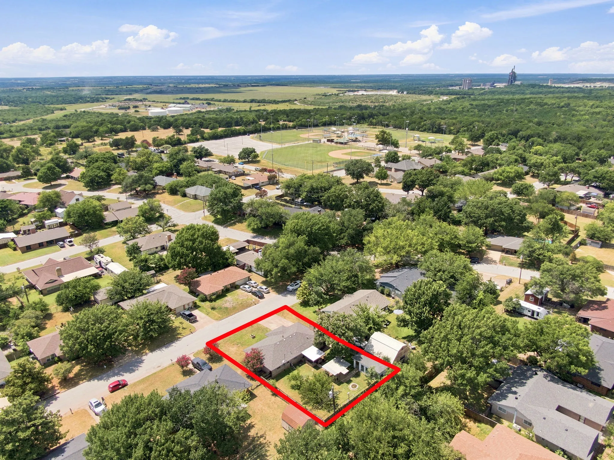 Aerial perspective showcasing a residential property surrounded by mature trees