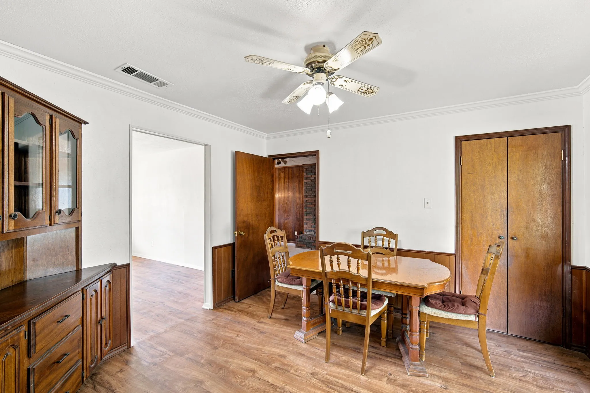 Dining area featuring wood-finish flooring, white walls, and crown molding