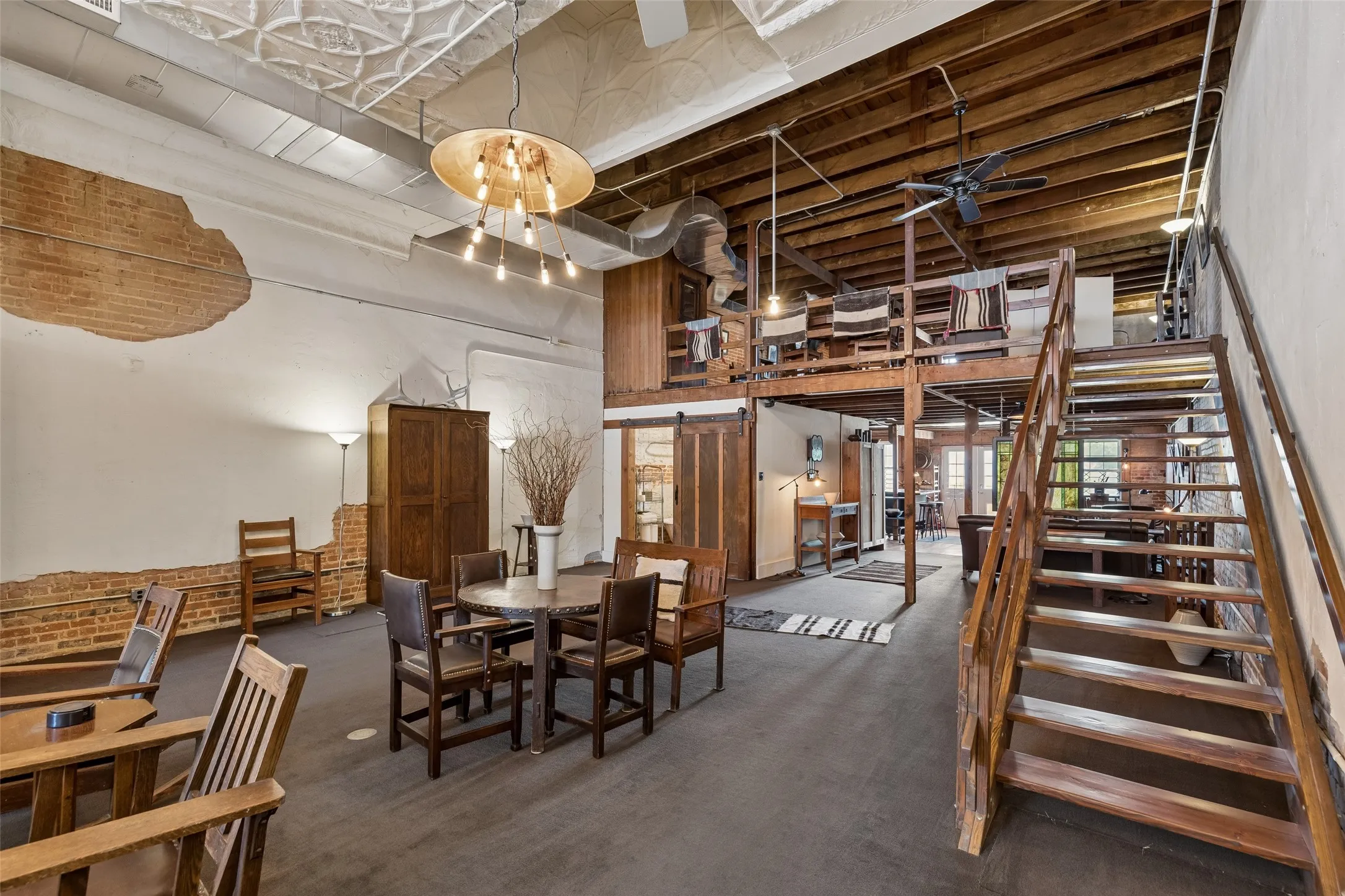 Open-concept interior featuring exposed brick accents, a pressed tin ceiling, and wood-beam ceiling details