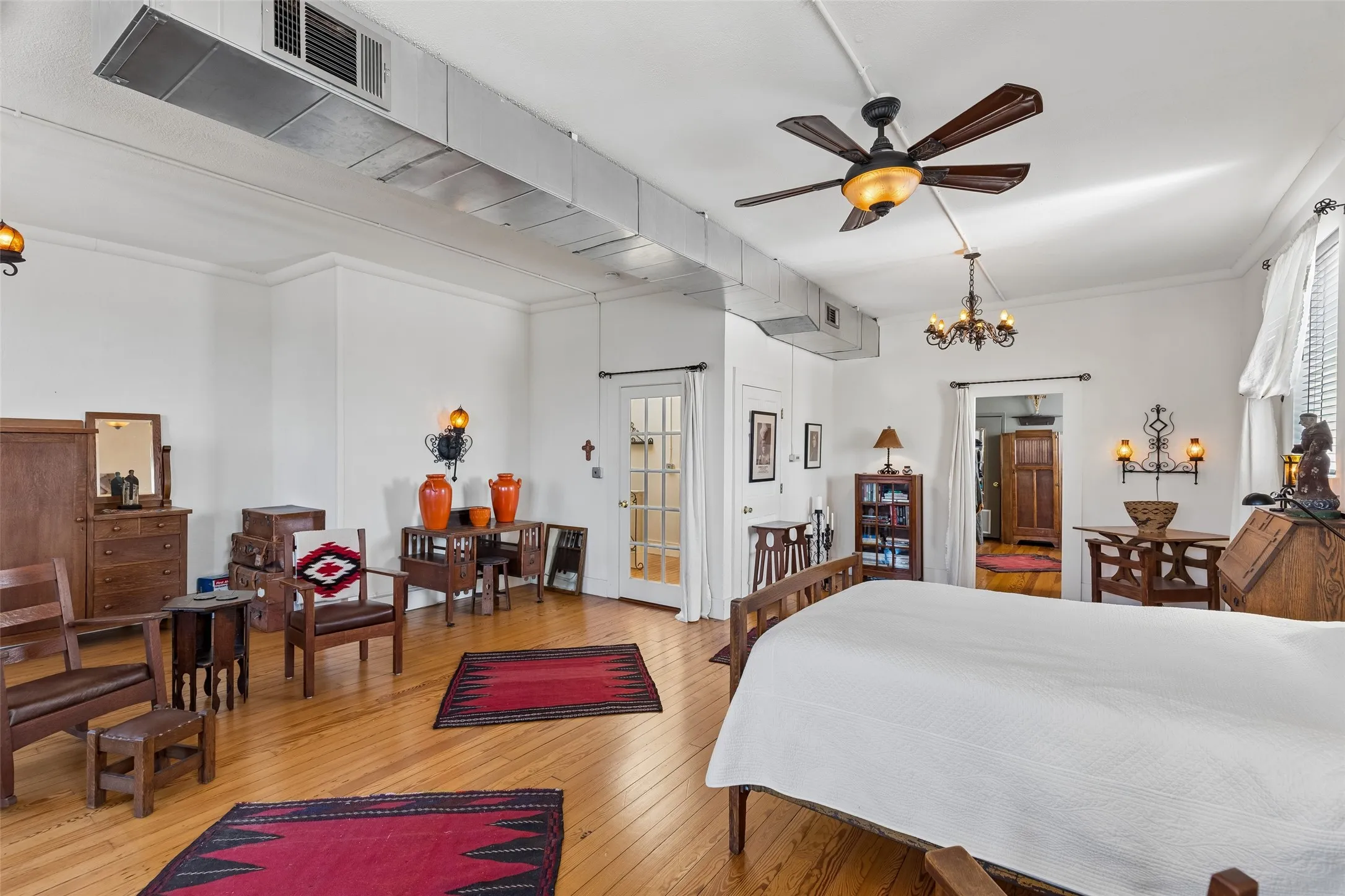 Spacious room featuring wood-finish flooring, exposed ductwork, and white walls with crown molding