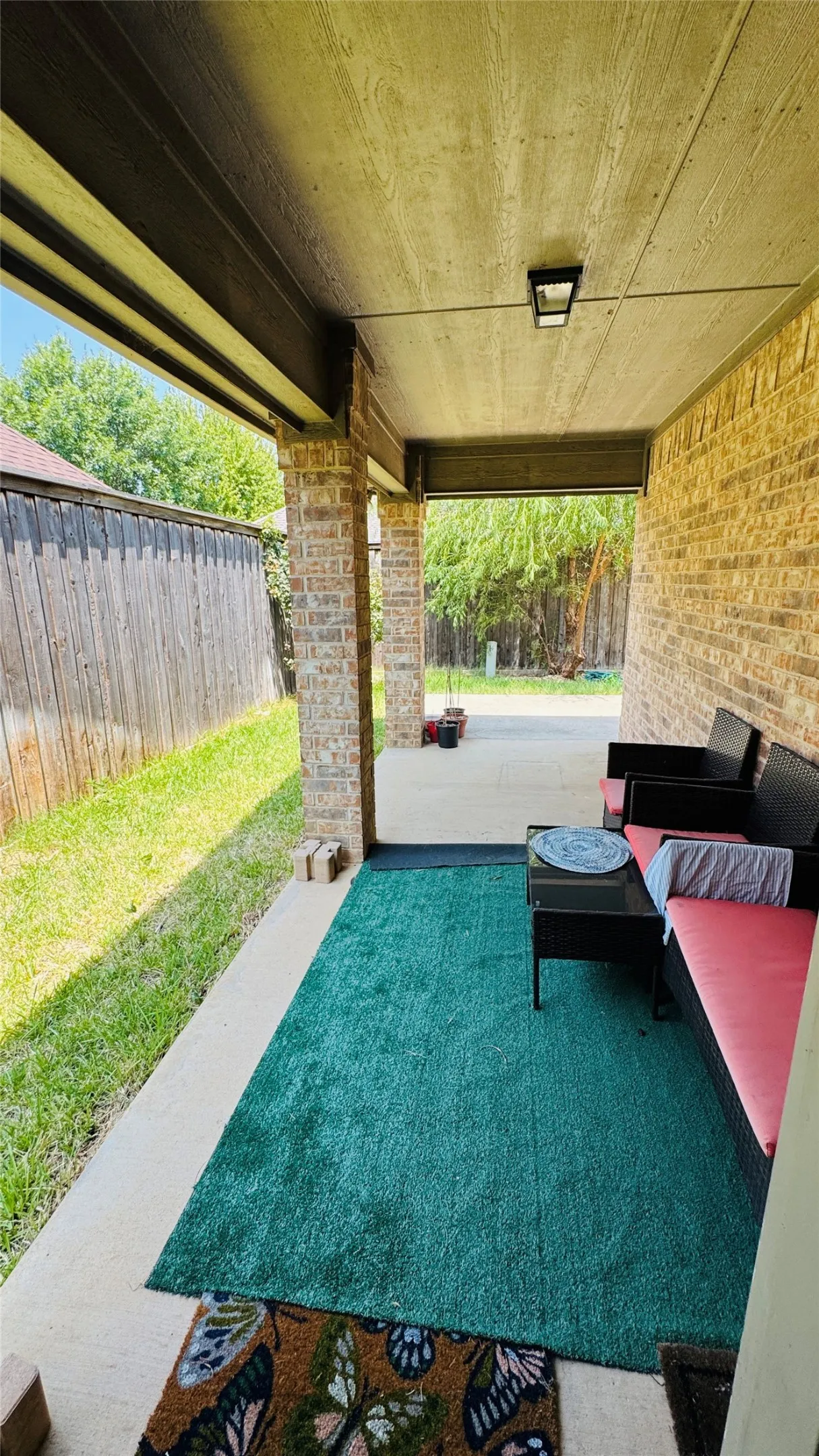 Covered patio featuring brick columns, a light fixture, and a concrete surface