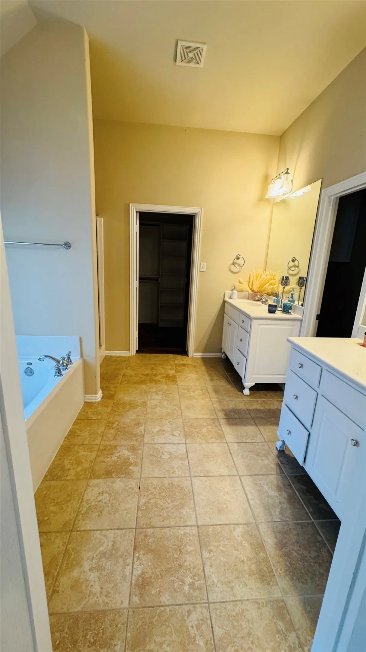 Spacious bathroom featuring a built-in tub, tiled flooring, a single vanity with storage, and an additional storage cabinet