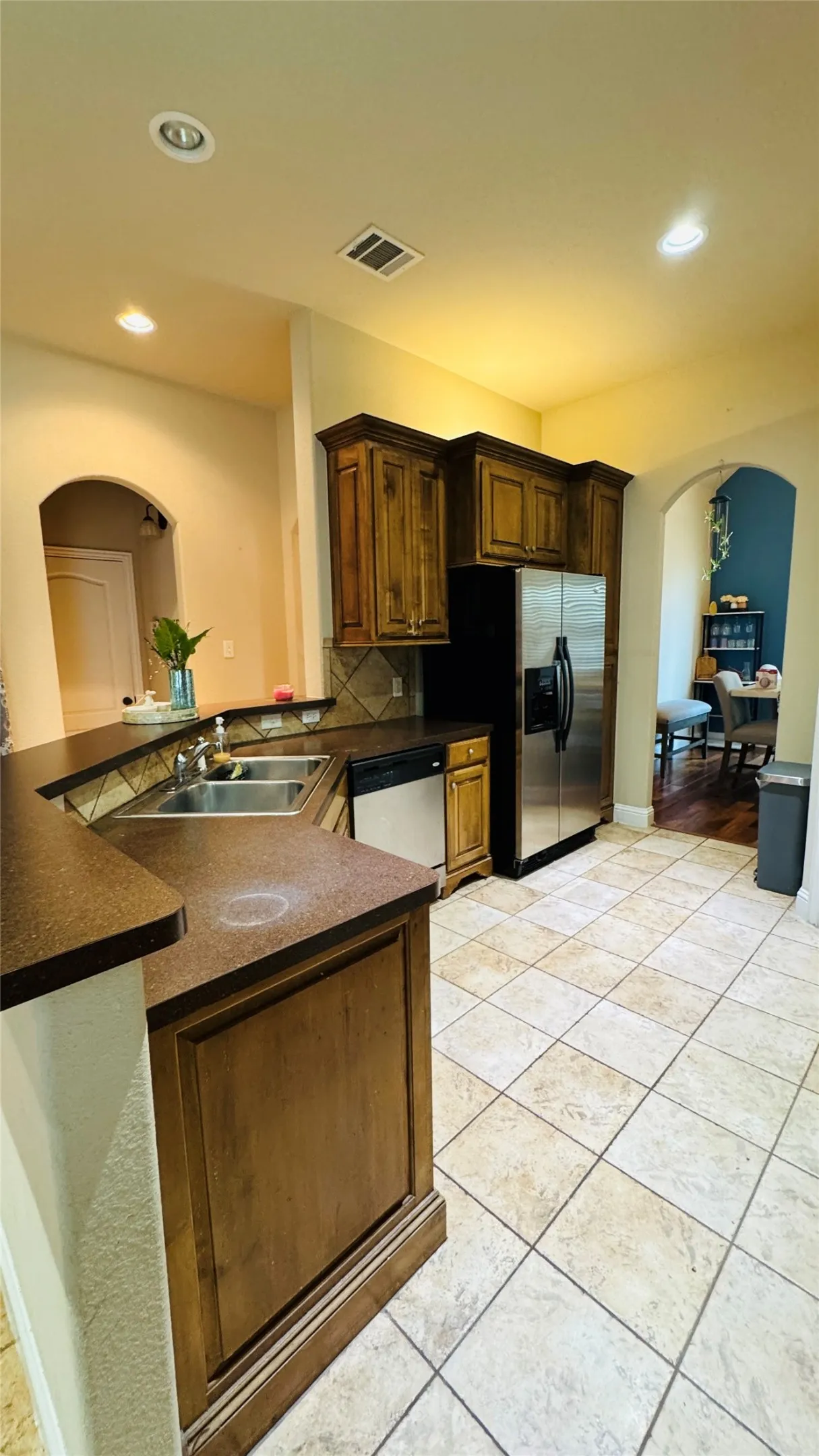 Kitchen featuring tile flooring, dark wood cabinetry, a double basin sink, and stainless steel appliances