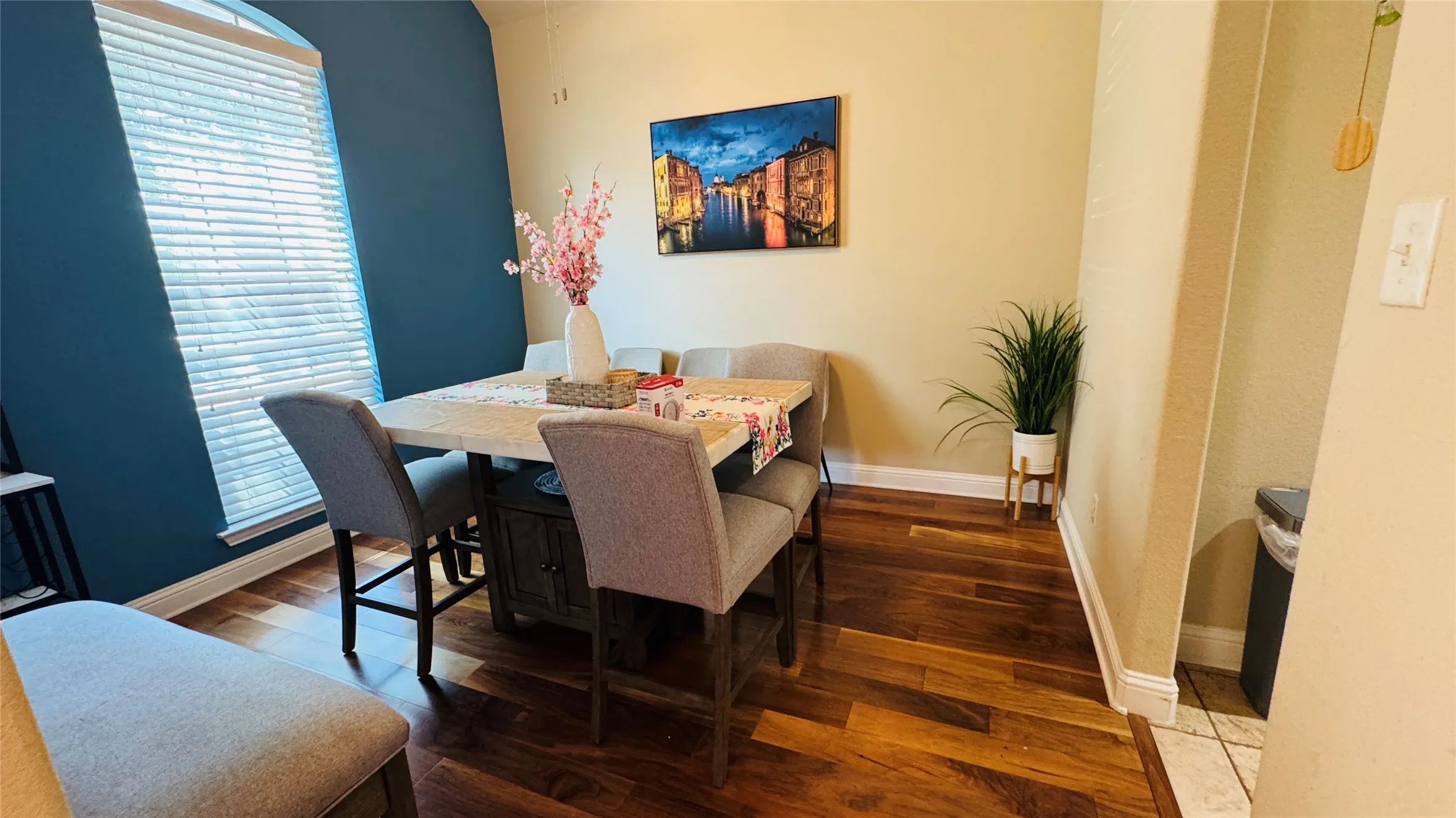 Hardwood-finish flooring, arched window with blinds, two-tone wall paint, white baseboards